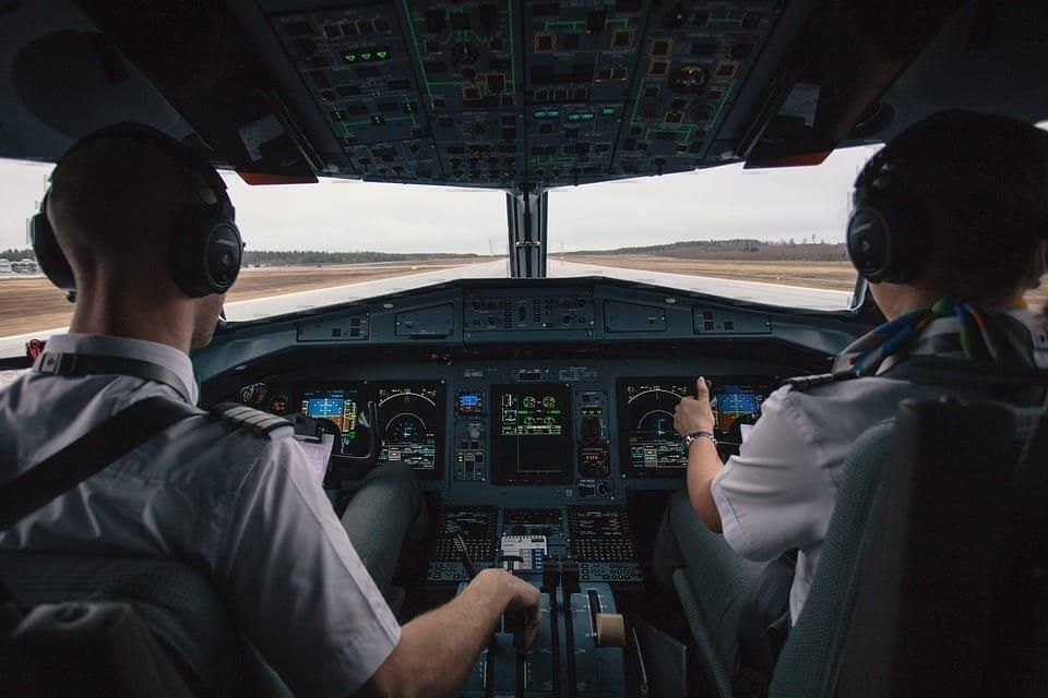 Two pilots sitting in a cockpit flying a plane.