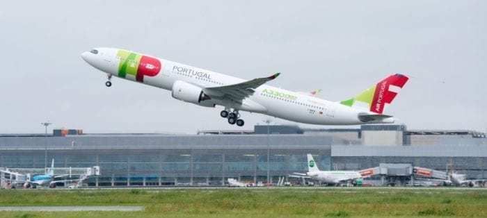 A TAP Air Portugal Airbus A330neo seen taking off with an airport in the background.
