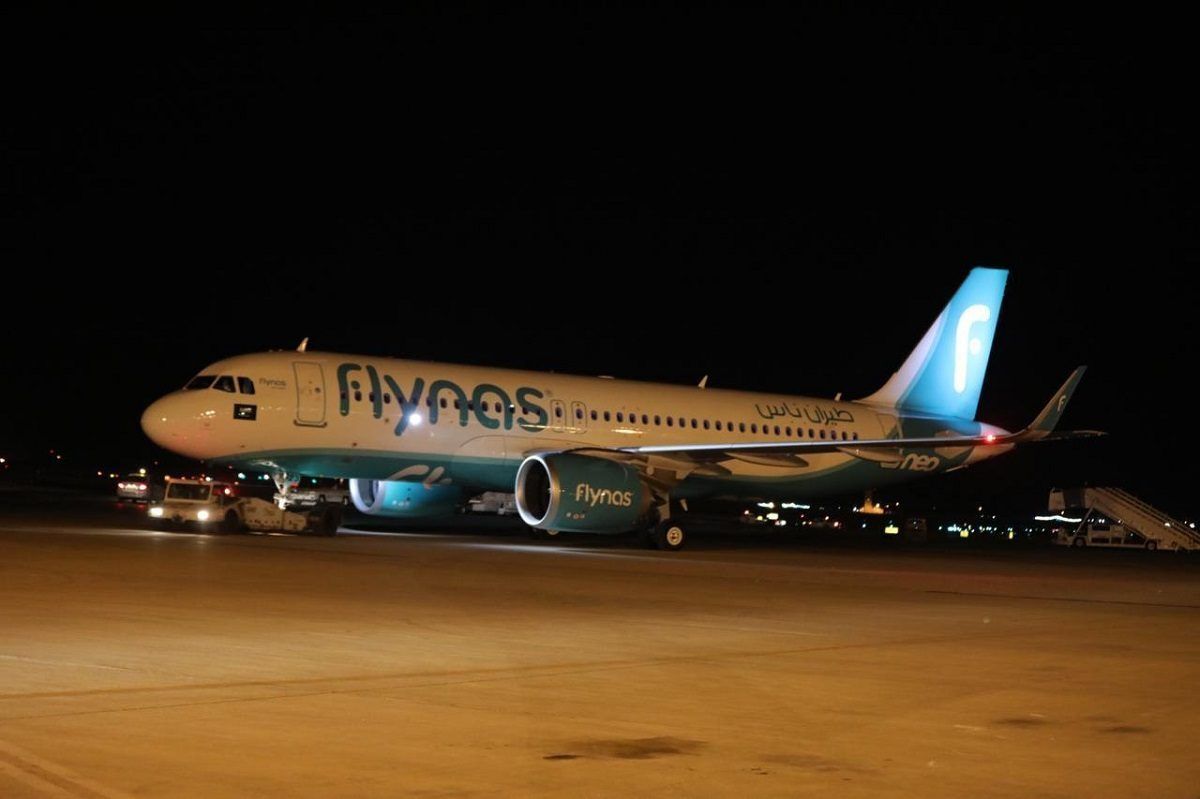 Flynas airliner at airport gate in dark