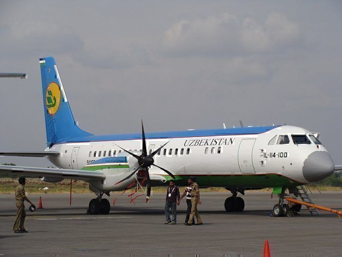 An Uzbekistan Airways Ilyushin IL-114-100 parked at an airfield.