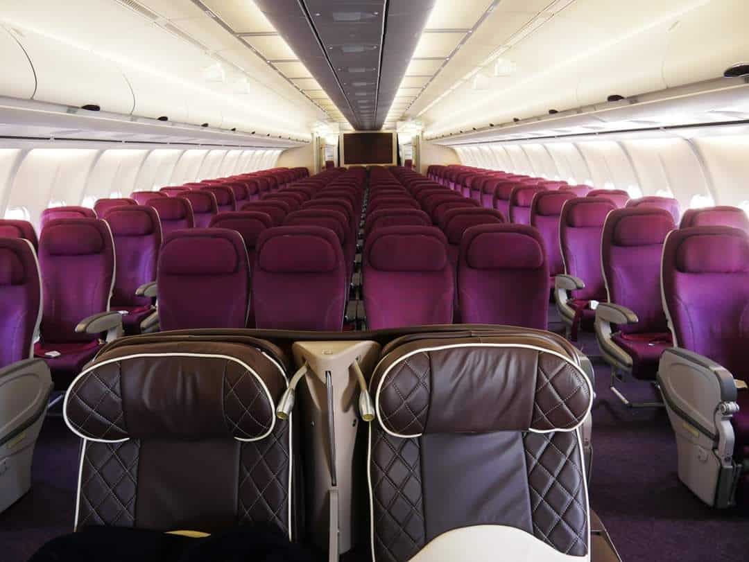 Onboard the Azman Air Airbus A340, looking at two Business Class seats and dozens of economy seats.