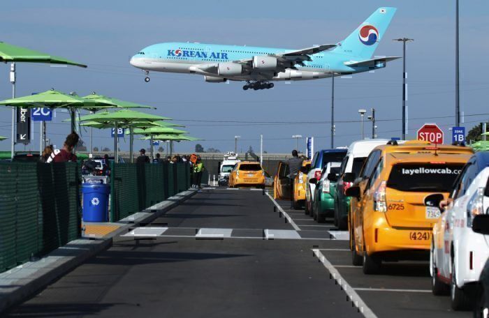 A Korean Air plane lands as taxis are lined up at the new 'LAX-it' ride-hail passenger pickup lot at Los Angeles International Airport