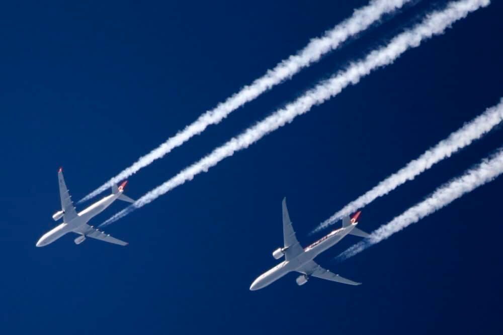 2 commercial jets fly with contrails