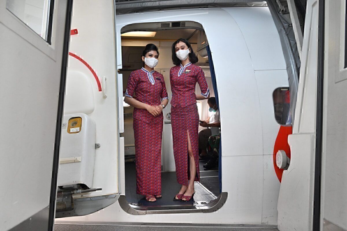 Two cabin crew standing at the door of an aircraft