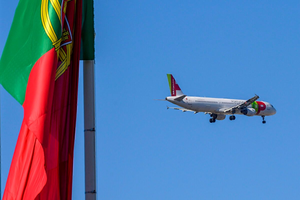 TAP Portugal airplane flying past a portuguese flag