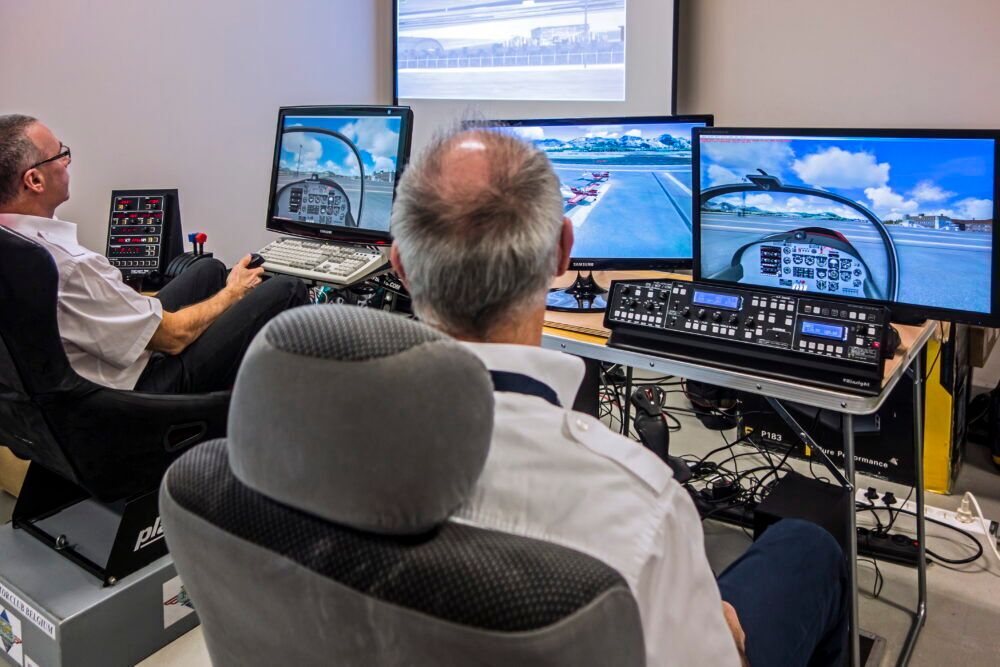 Two men navigating virtual airplane in amateur flight simulator