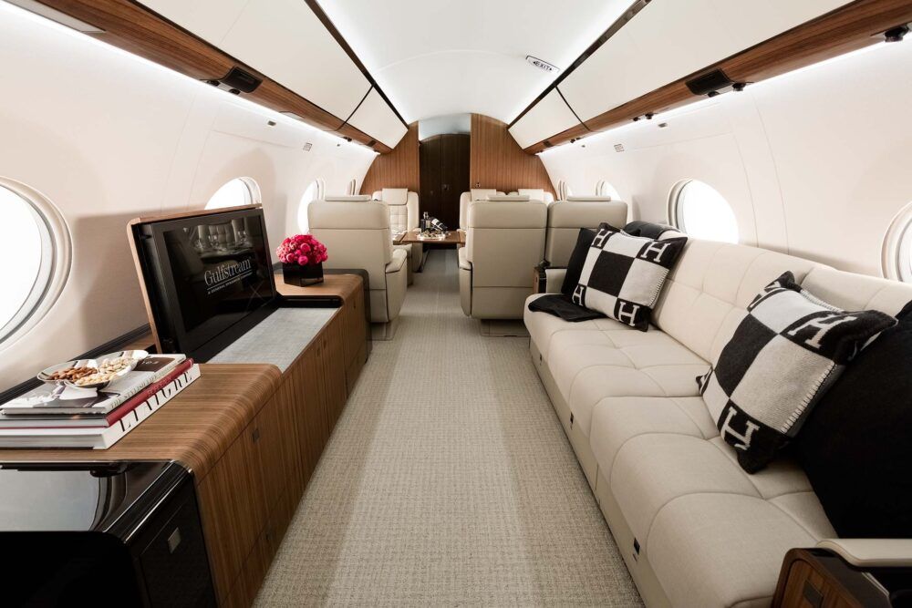 A Gulfstream G650/G650ER living area, featuring a couch, television, and dining compartment for 6.