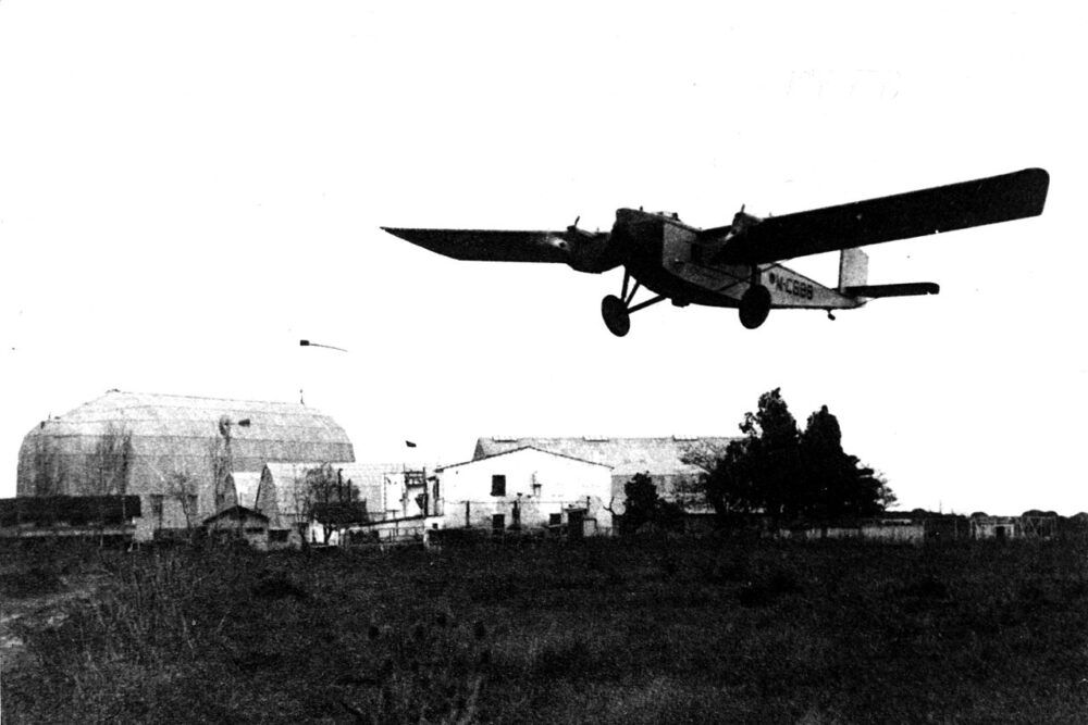 A light aircraft flying over a farm.