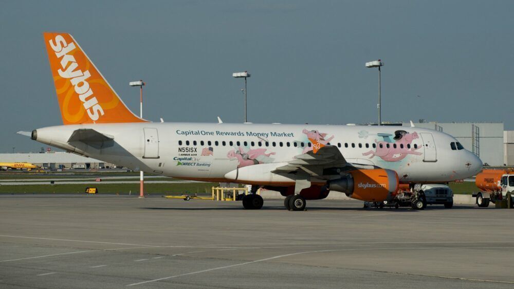 A Skybus A319 with flying pigs on its livery at an airport.