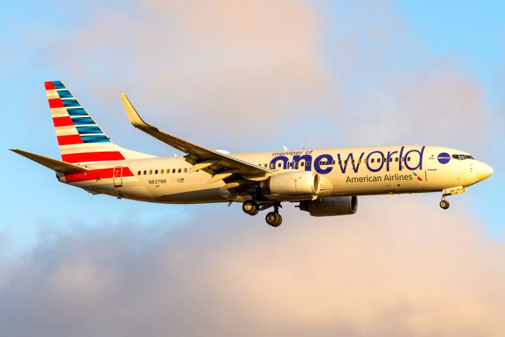 An American Airlines aircraft in oneworld alliance livery flying in the sky.