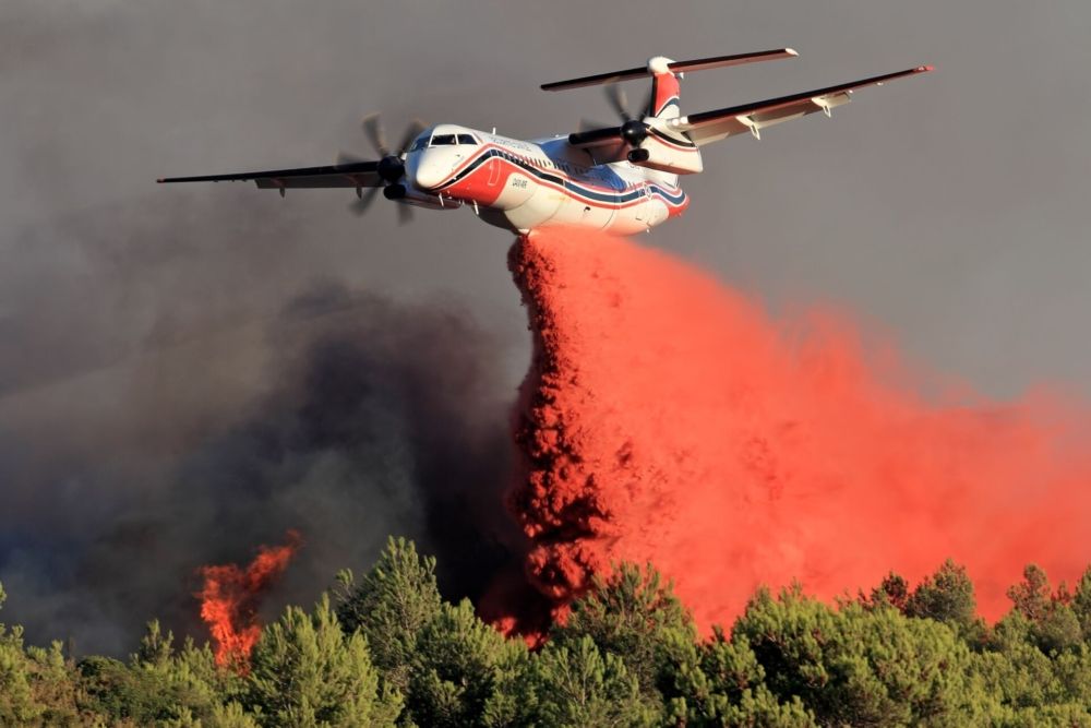 A Conair Dash 8 400 spreading fire retardant to put out a wildfire.