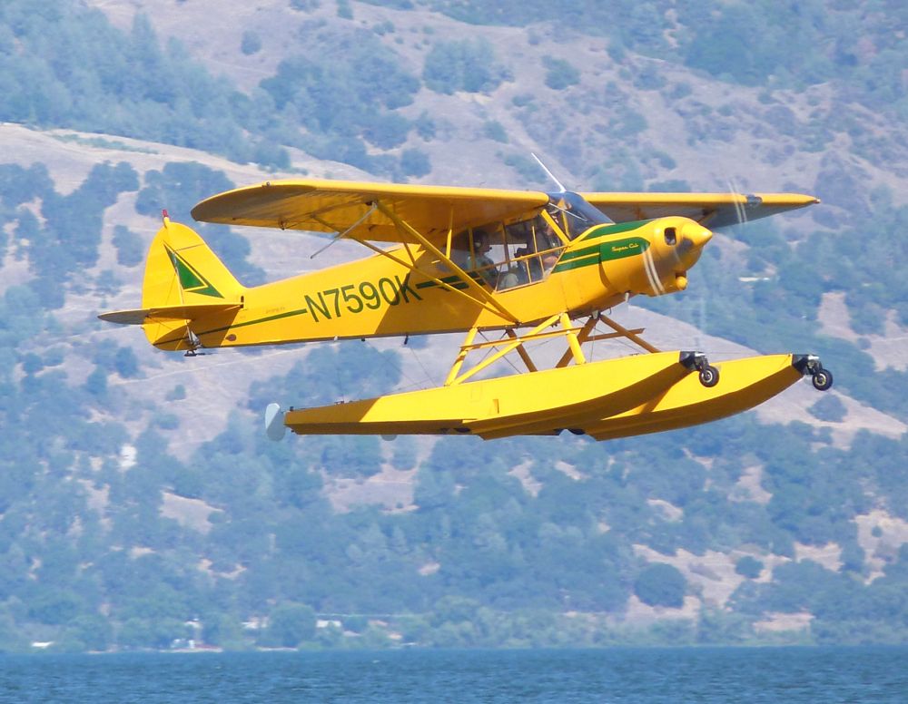 A small yellow Floatplane about to land.