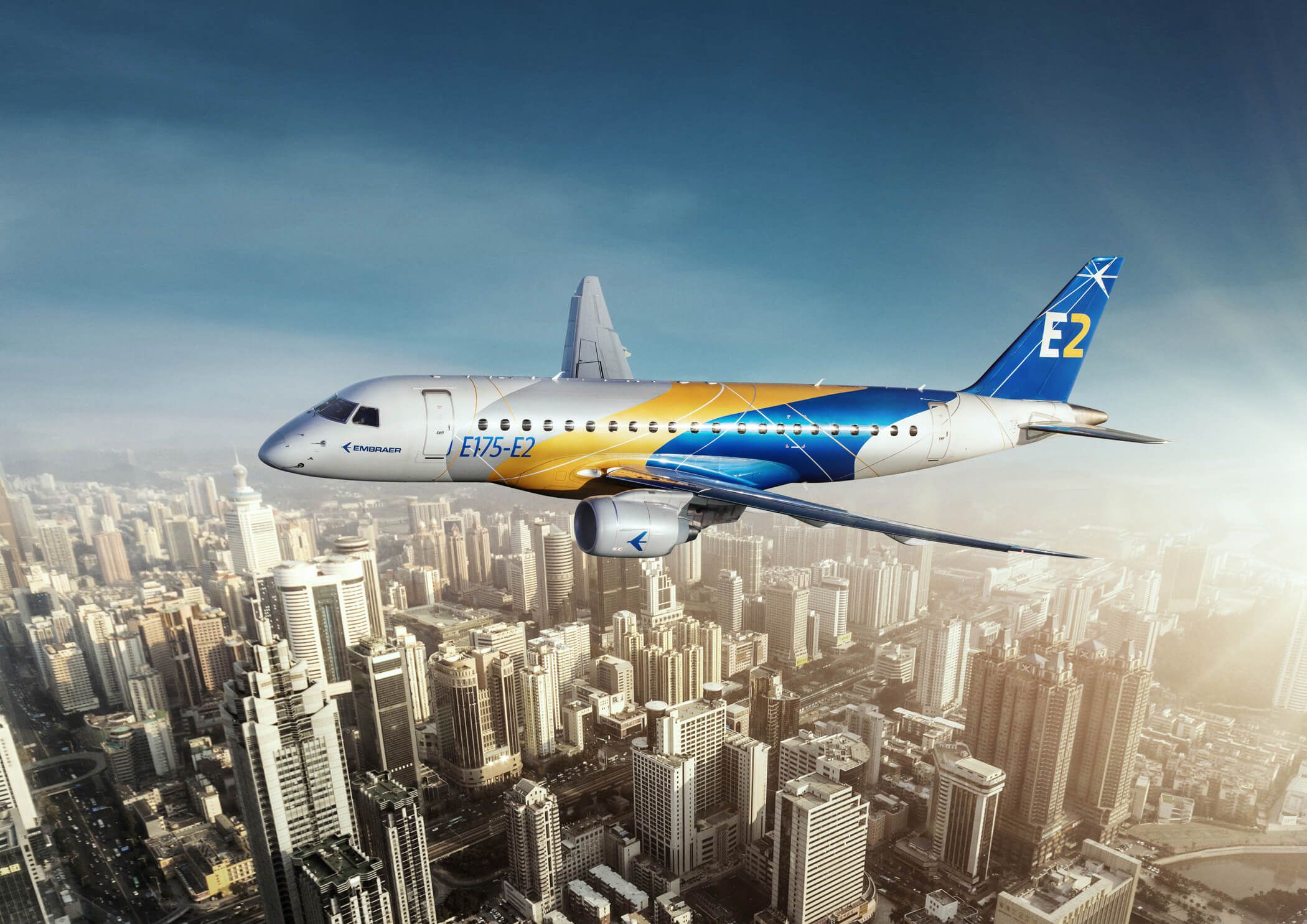 An Embraer E2 jet flying over a large city.