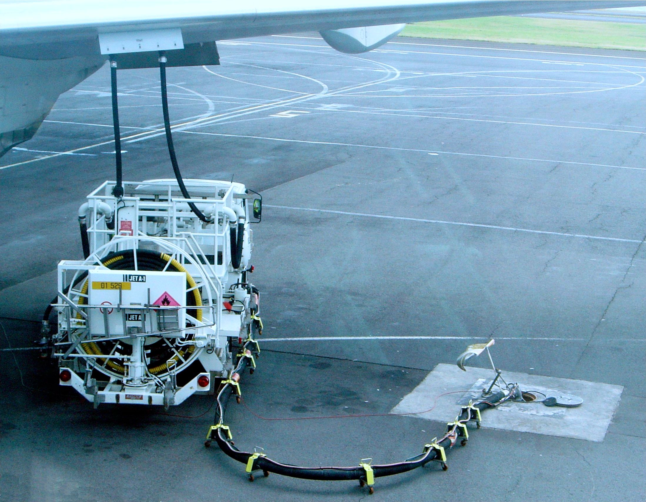 A refueling truck parked beneath an aircraft wing.