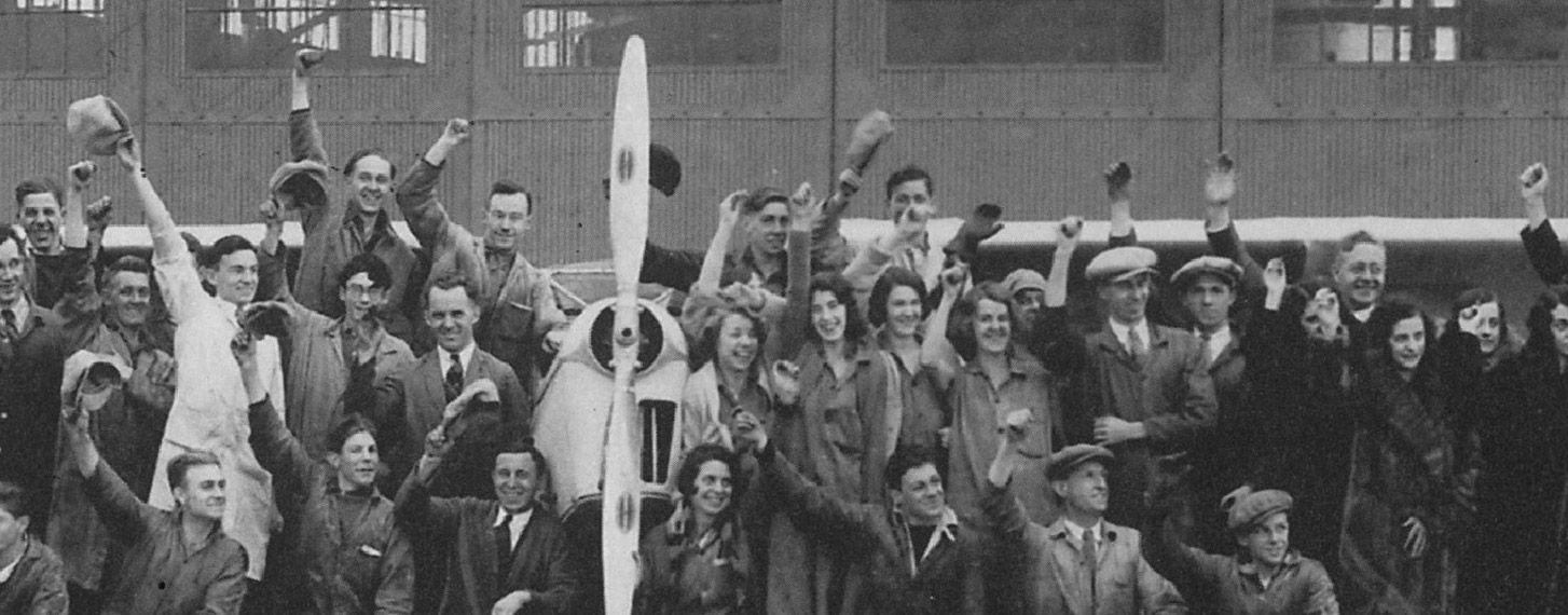 Several people celebrating near an old De Havilland Canada aircraft.