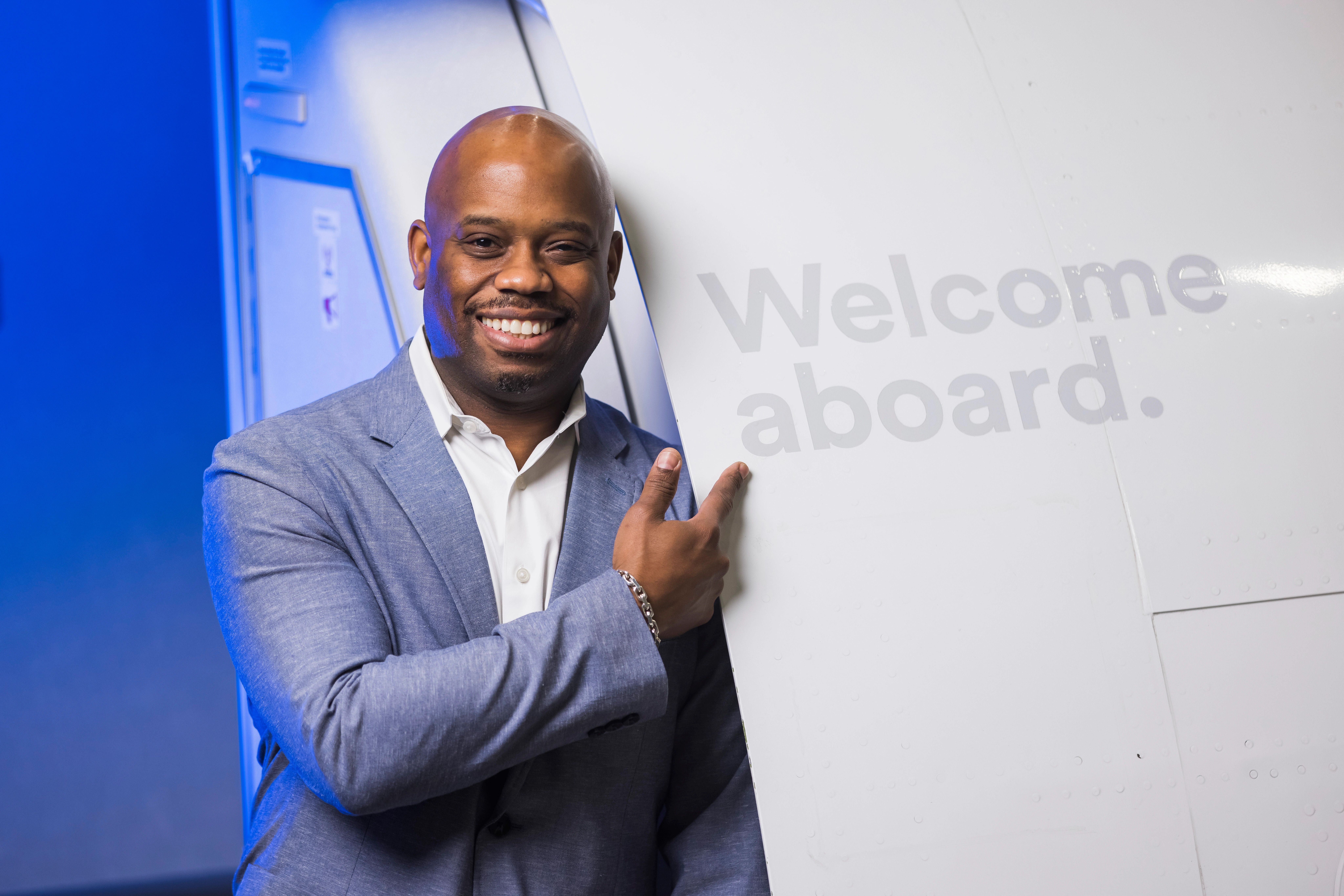 James Thomas, Alaska Airlines Director of Diversity, Equity and Inclusion Posing With the Alaska Airlines "Welcome aboard." Sign