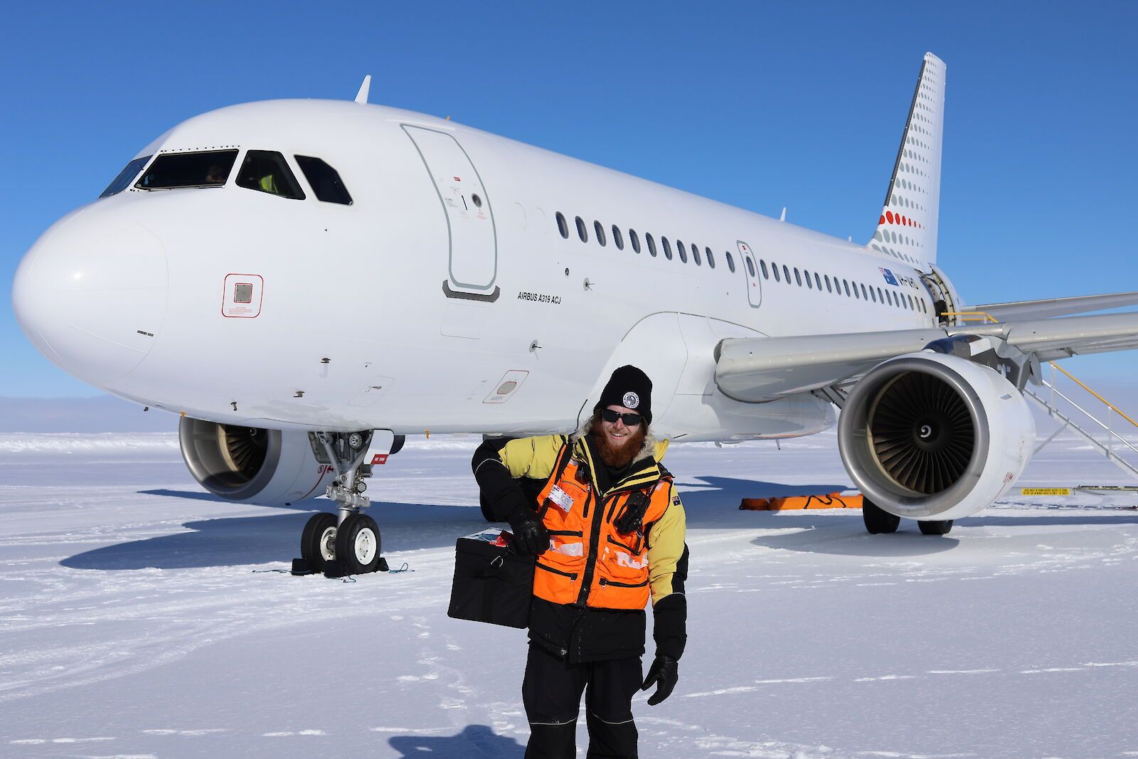 A worker standing in front of an aircraft on the ground in Antarctica.