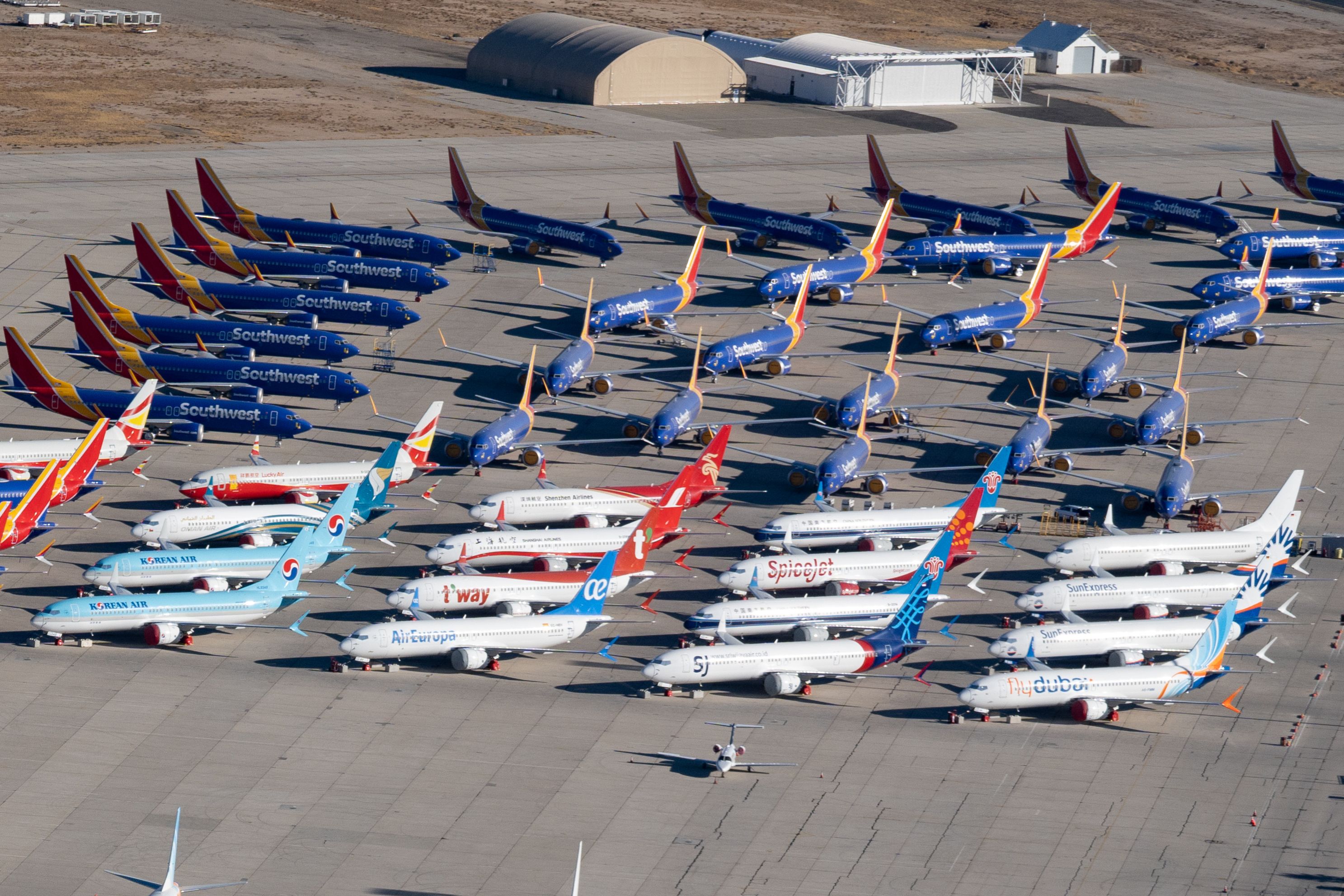 Dozens of Boeing 737 MAX 8 aircraft from many airlines parked at an airfield.