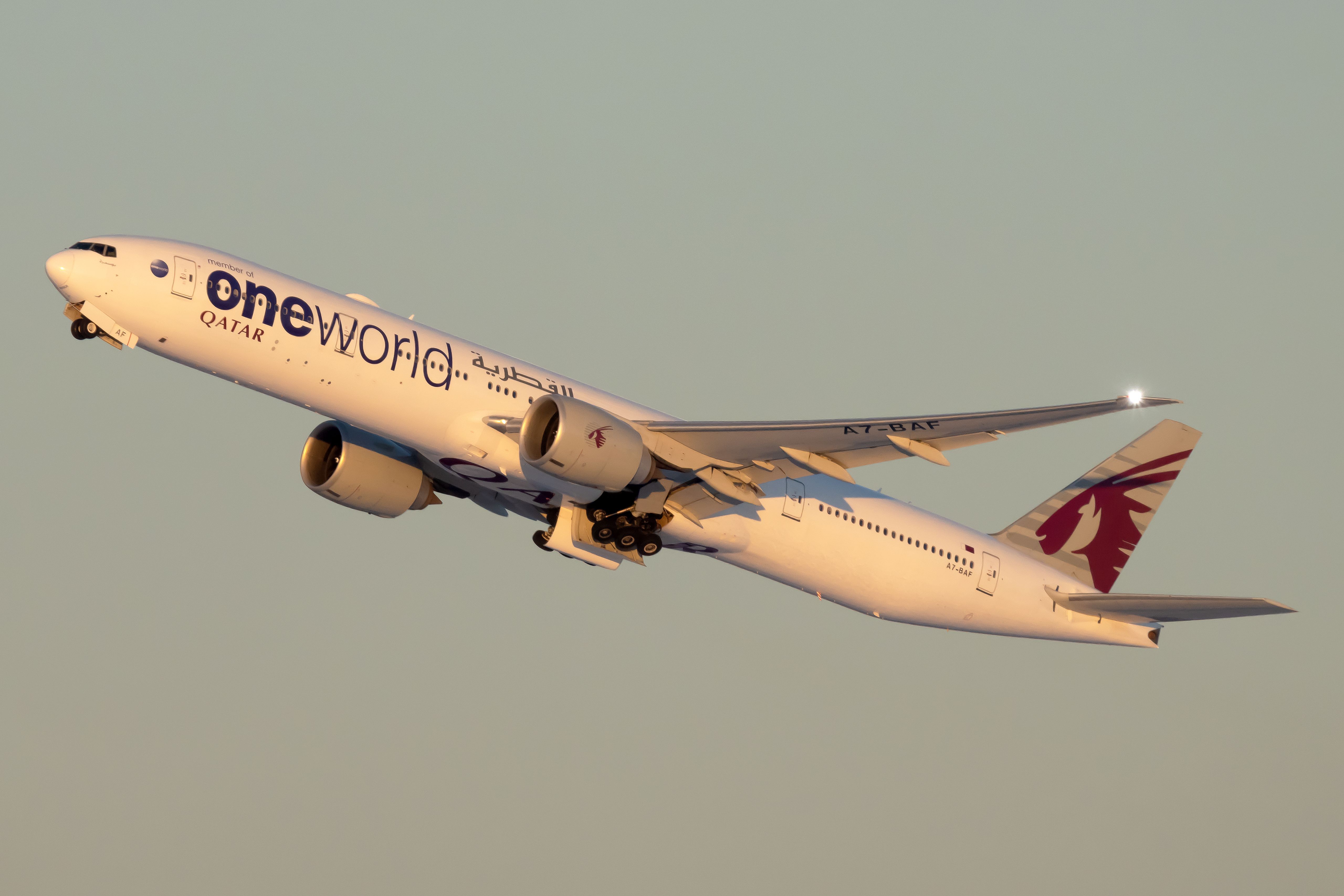 A Qatar Airways Boeing 777 in OneWorld Livery flying in the sky.