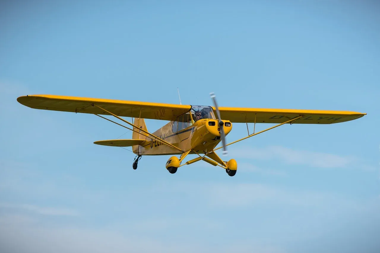 A Piper J-3 Cub flying in the sky.