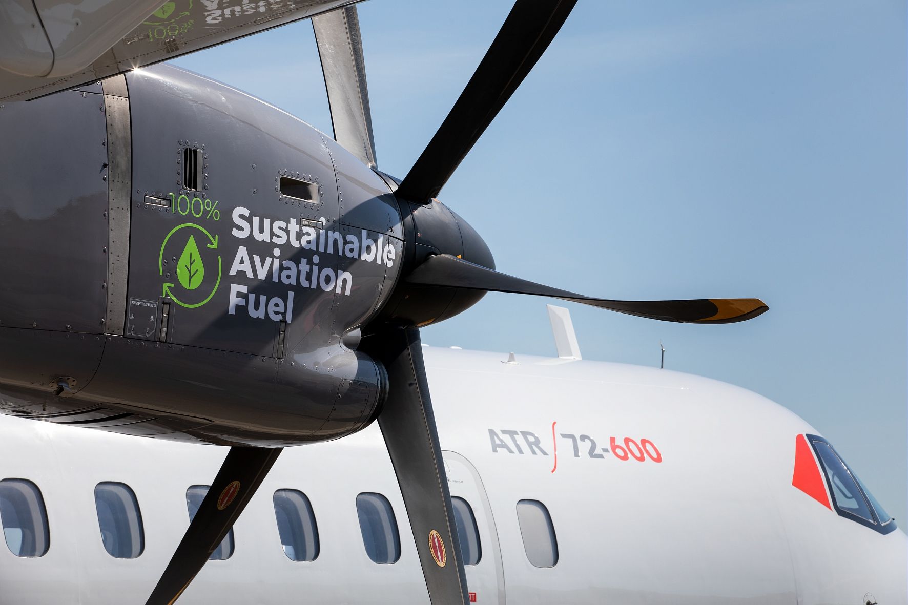 A closeup of the engine of an ATR aircraft with a 100% sustainable aviation fuel logo painted.