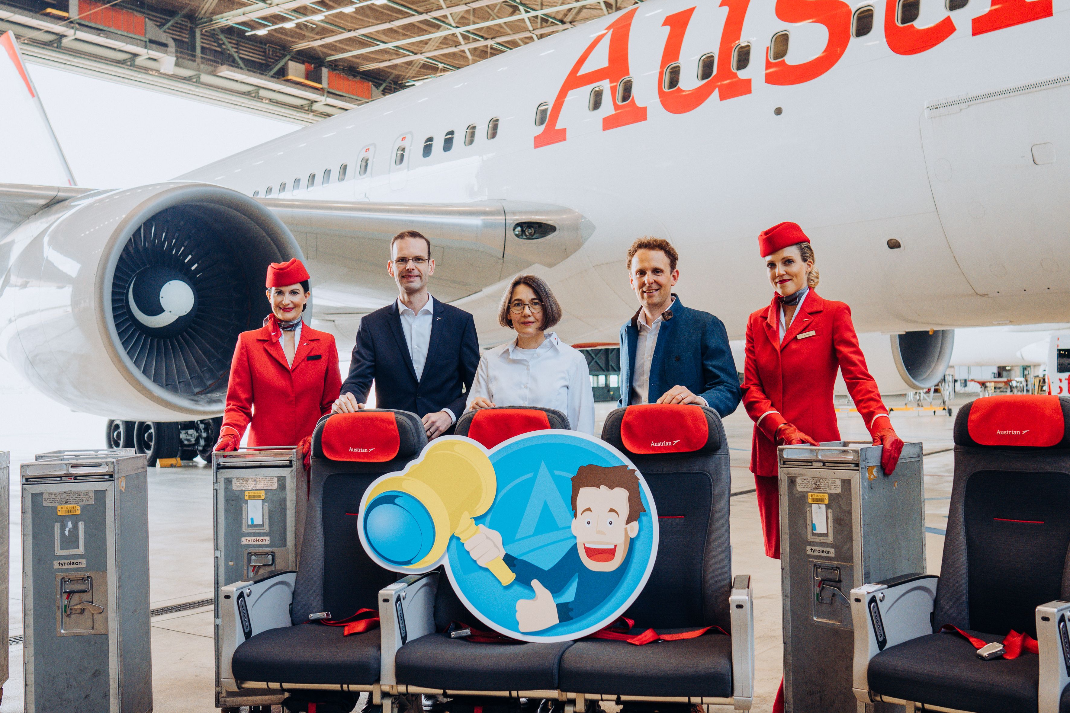 A group of Austrian Airlines employees standing in front of an aircraft with seats and trolleys
