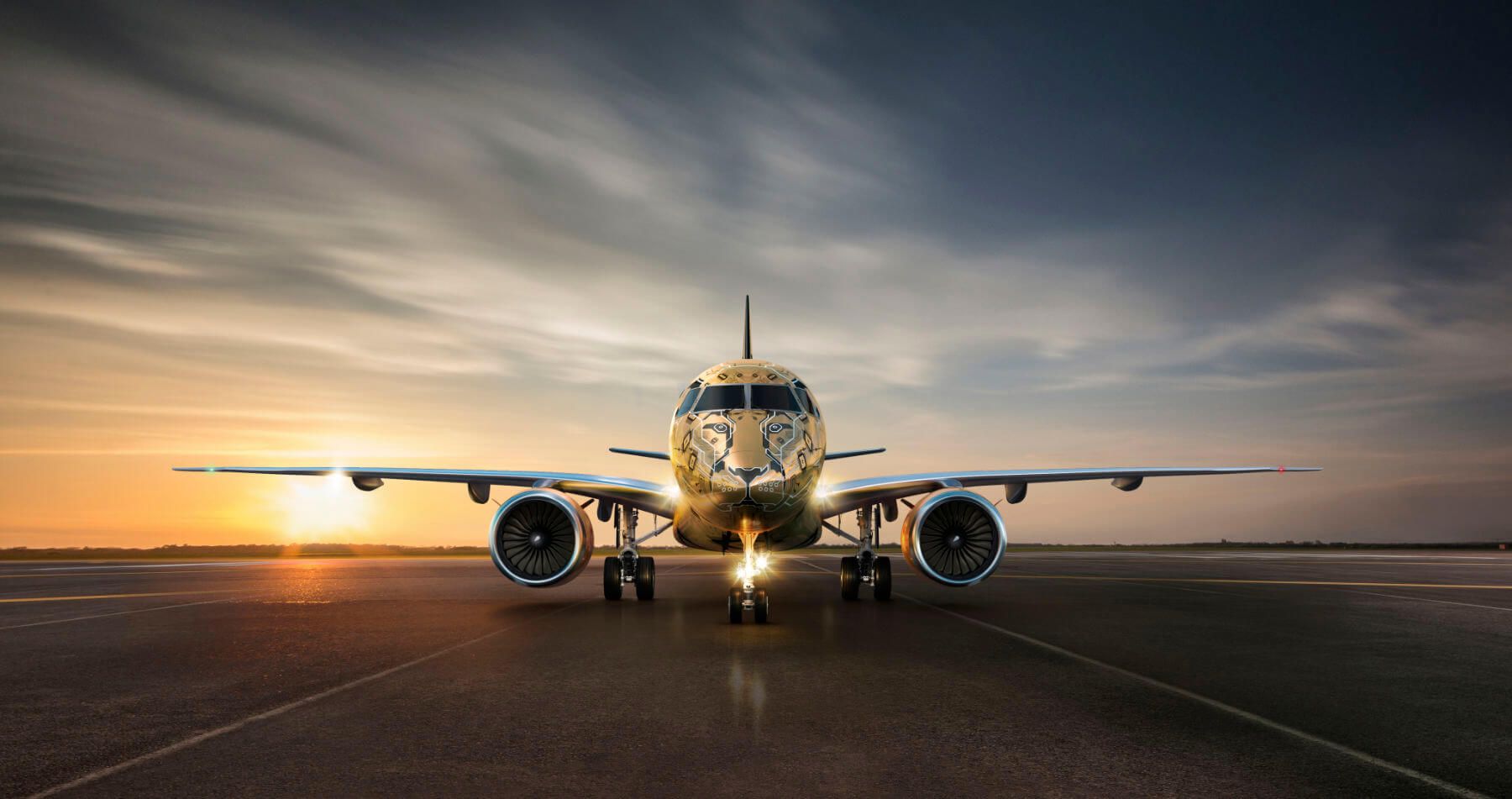 Embraer E175 on runway with sunset backdrop