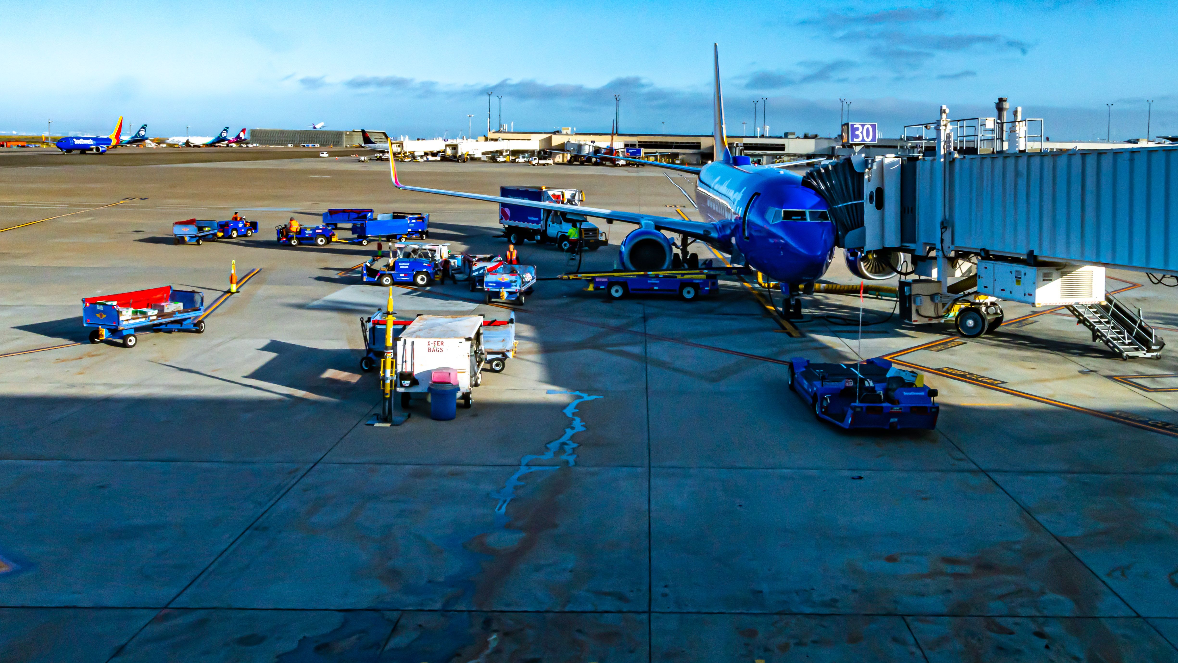 A Southwest Airlines Boeing 737-700 parked at an airport gate surrounded by luggage and other service vehicles.