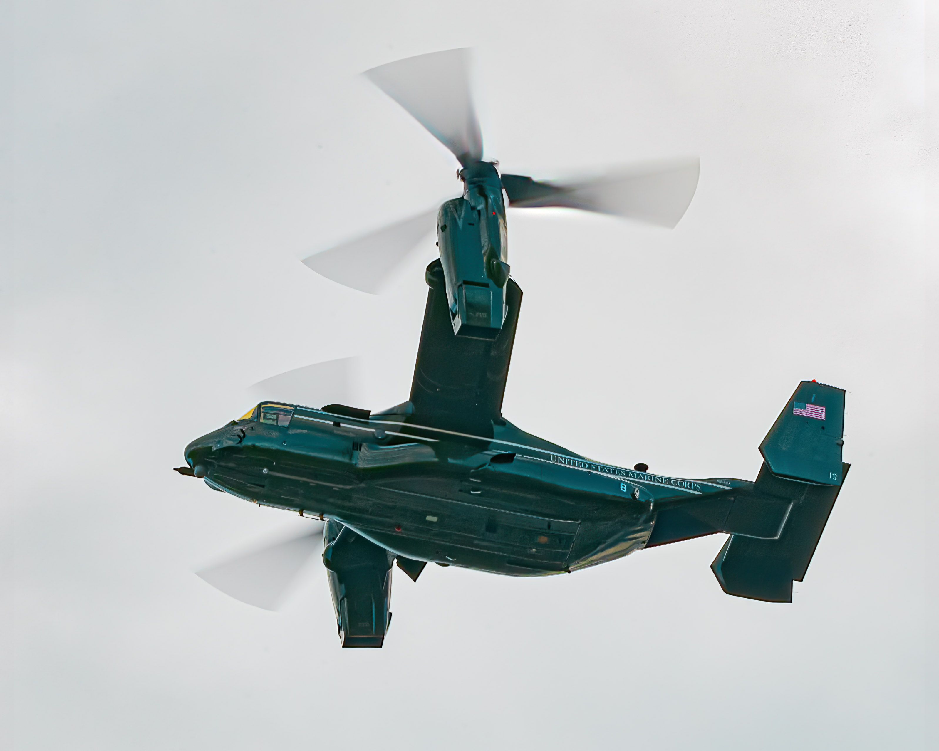 A USMC V-22 in helicopter mode flying in the sky.