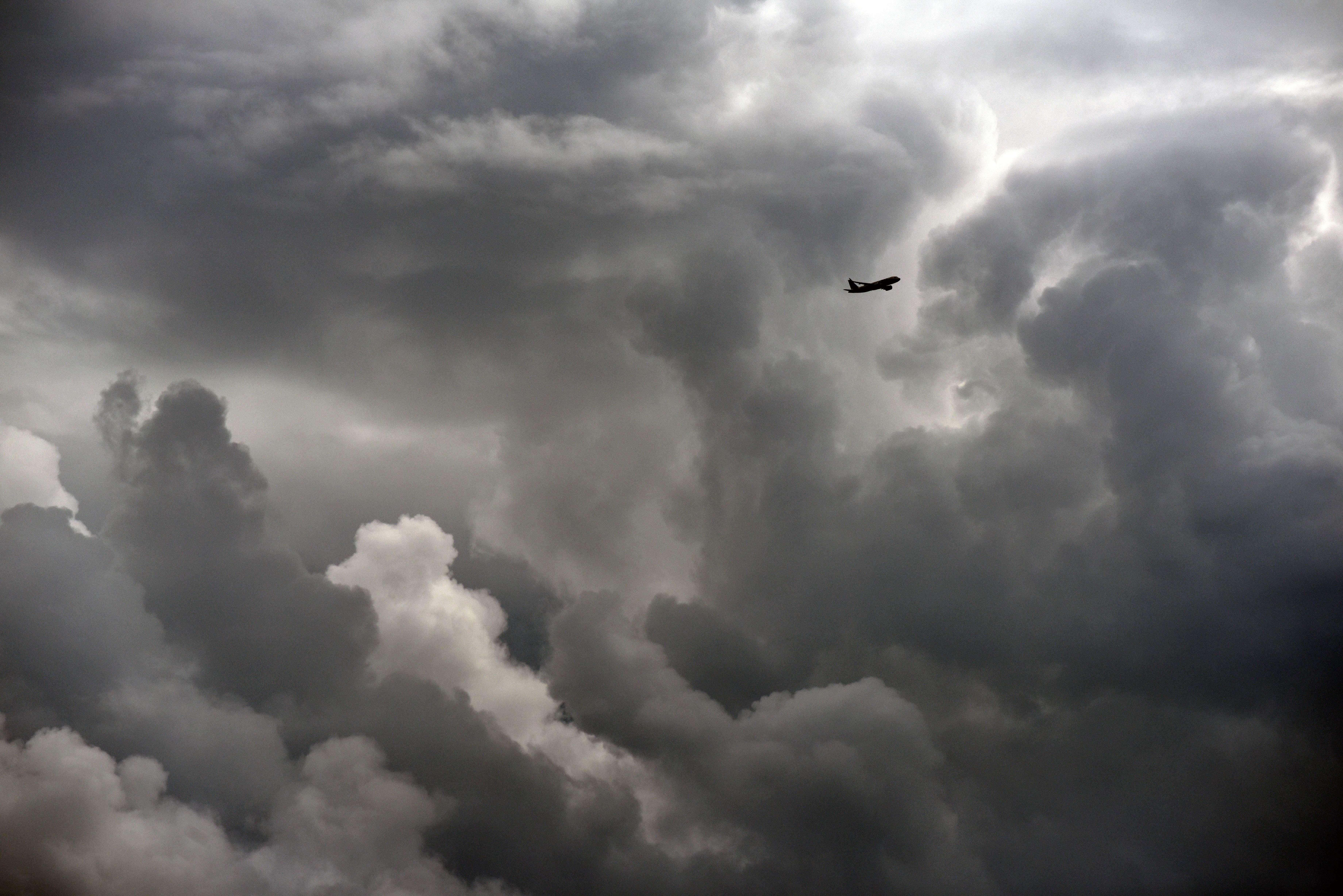 Plane traveling through storm clouds in sky