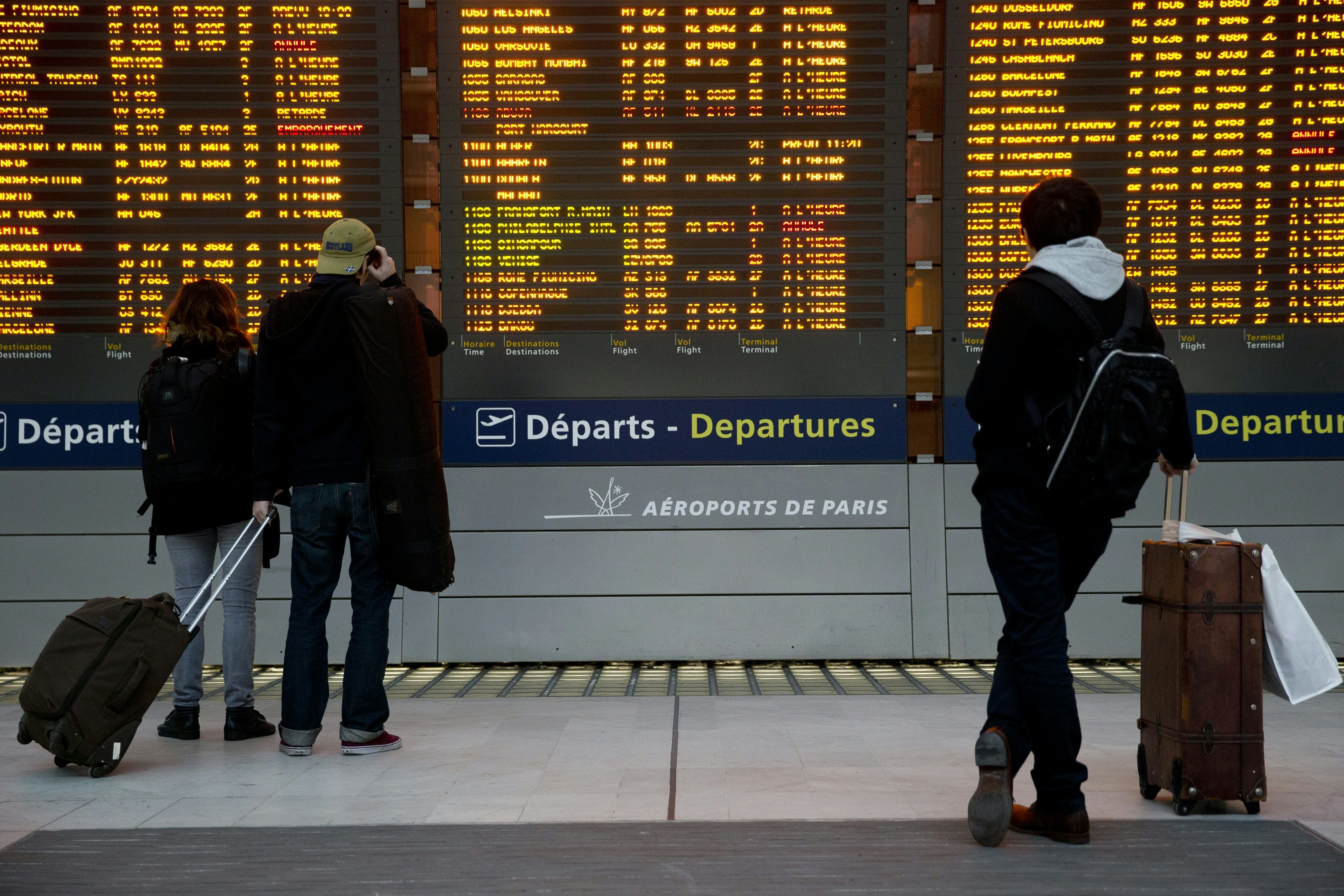 People in airport terminal looking at departures board