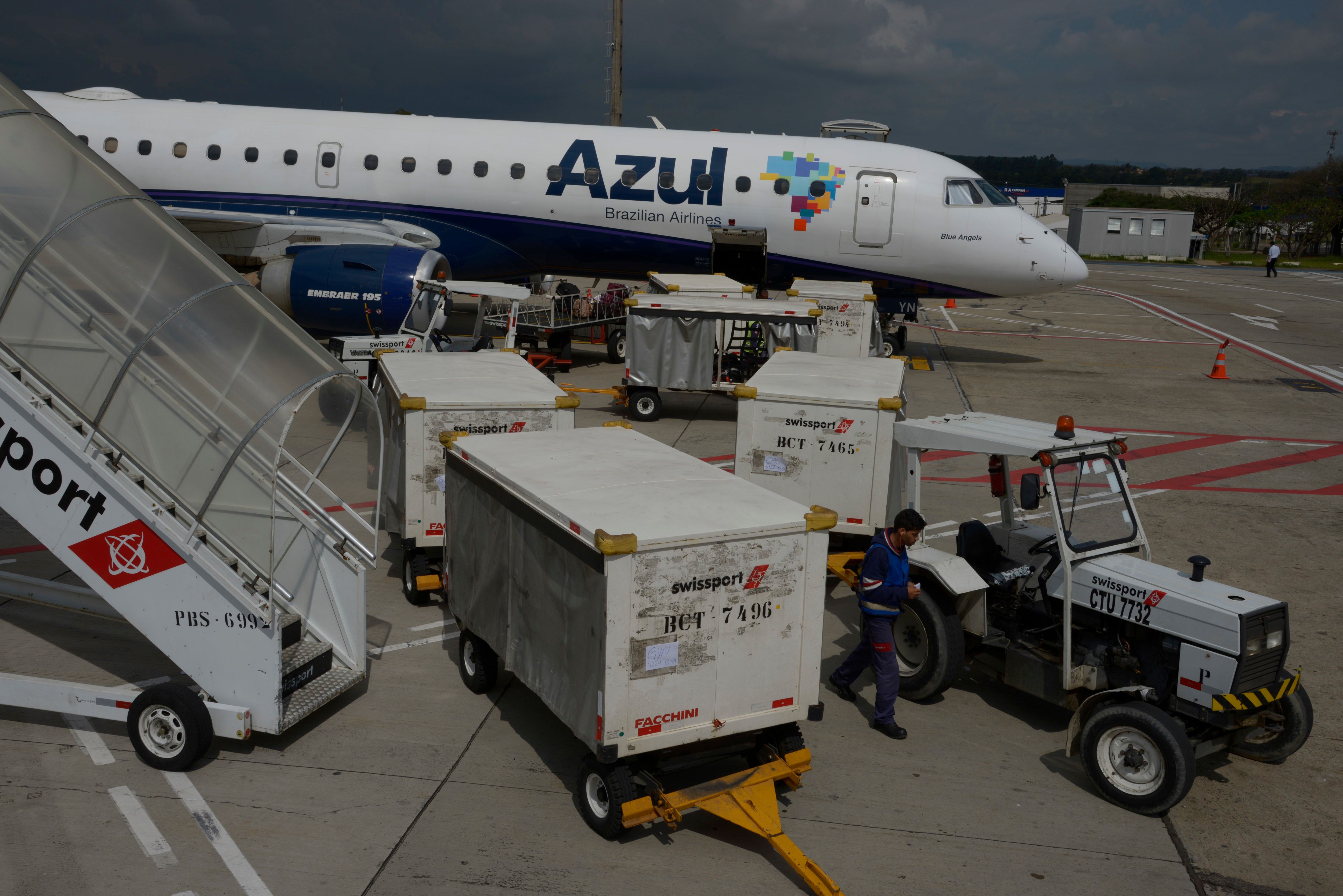 Ground crew members unload baggage from an Azul Linhas Aereas Brasileiras Embraer E190 jet at Viracopos International Airport in Campinas, Brazil-542638970