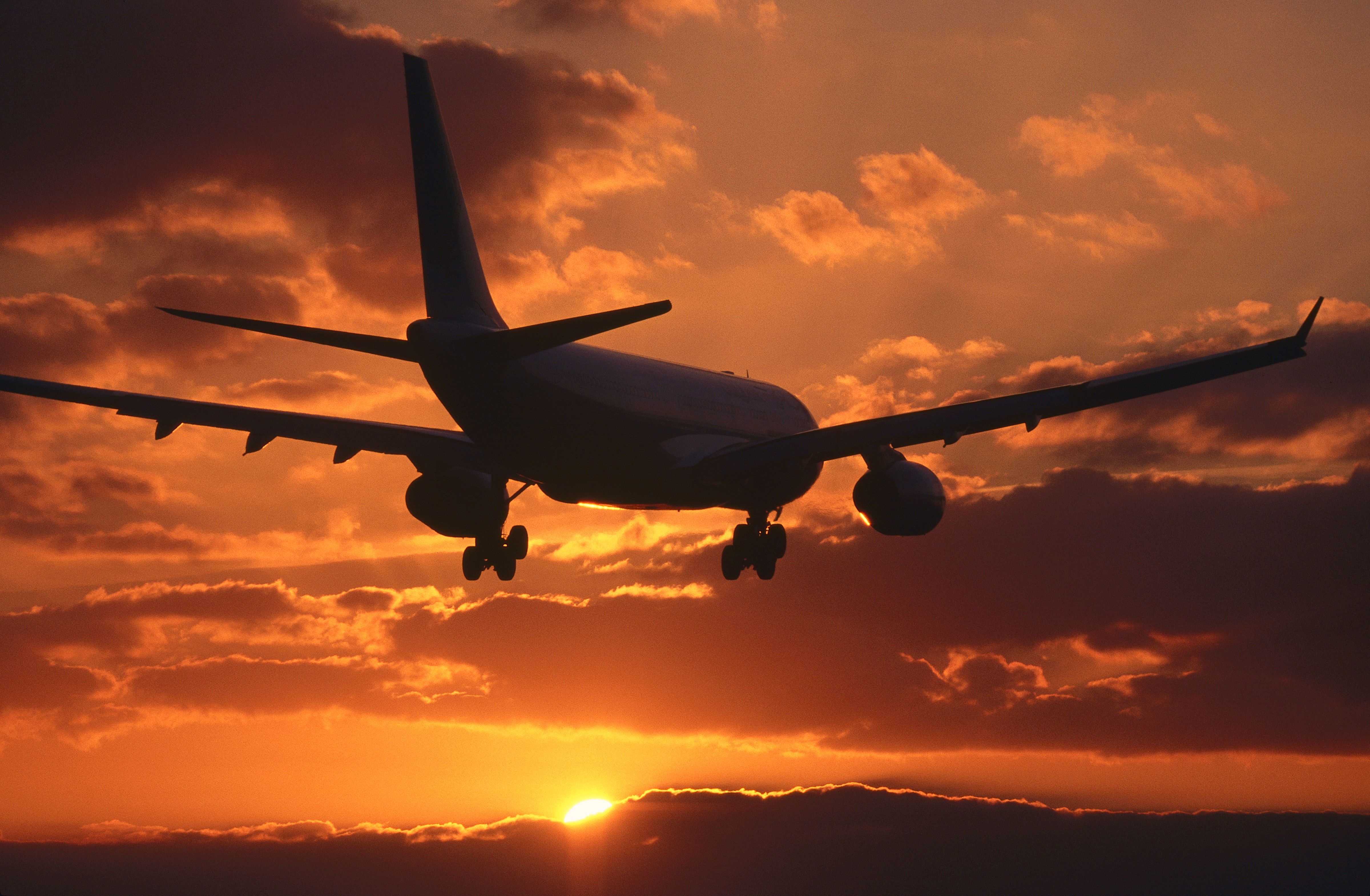 Airplane silhouette against a sunset sky landing