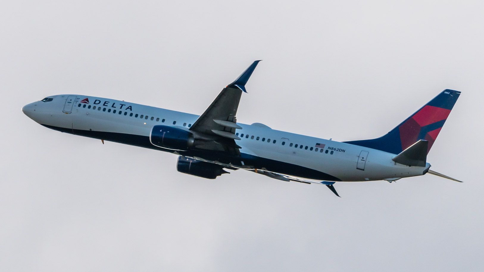 A Rising Delta Air Lines' Boeing 737-900ER against an overcast sky