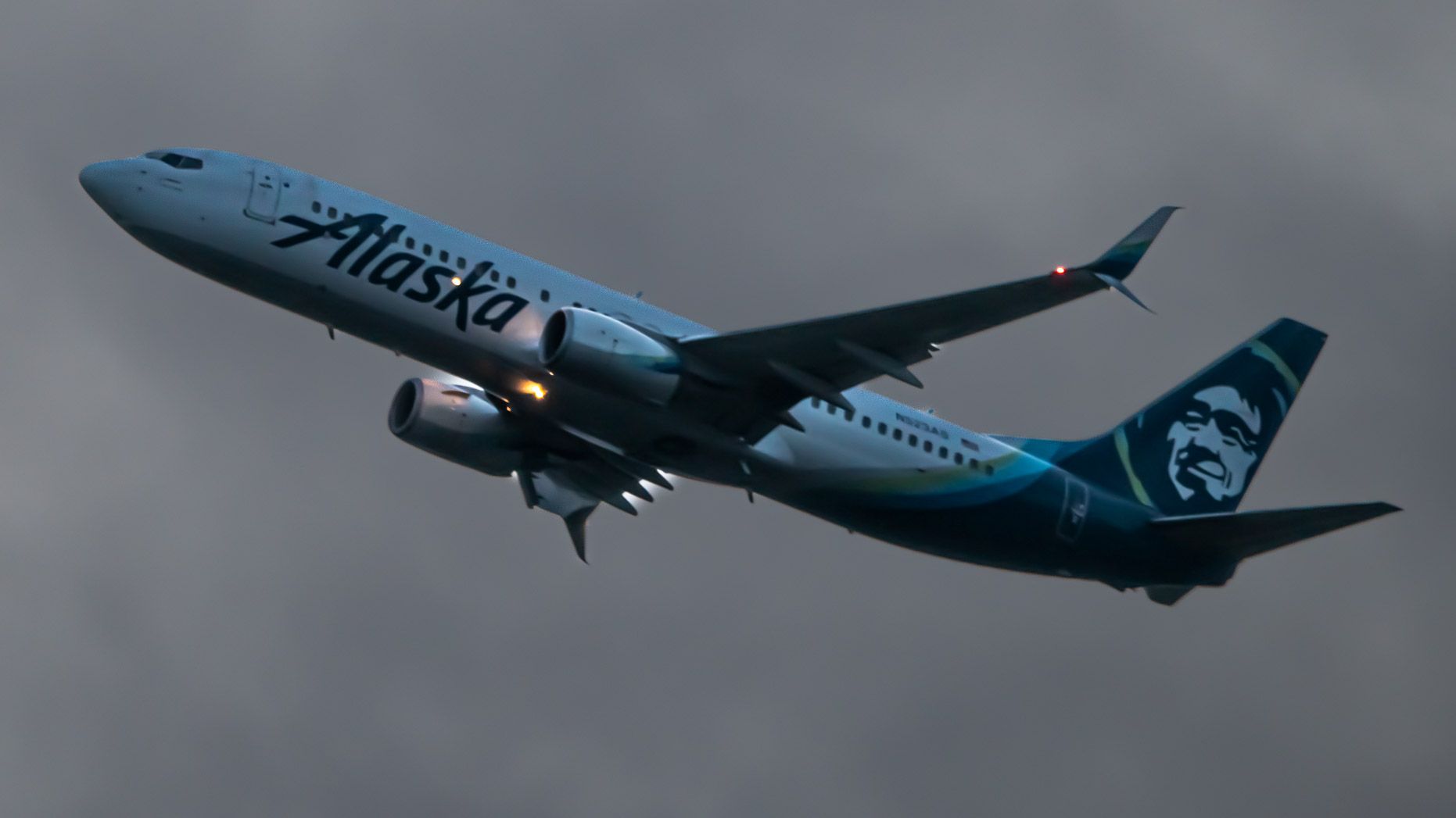 RISING BOEING 737-890(WL) OF ALASKA AIRLINES IN OVERCAST with aircraft beacons on and gear tucked in