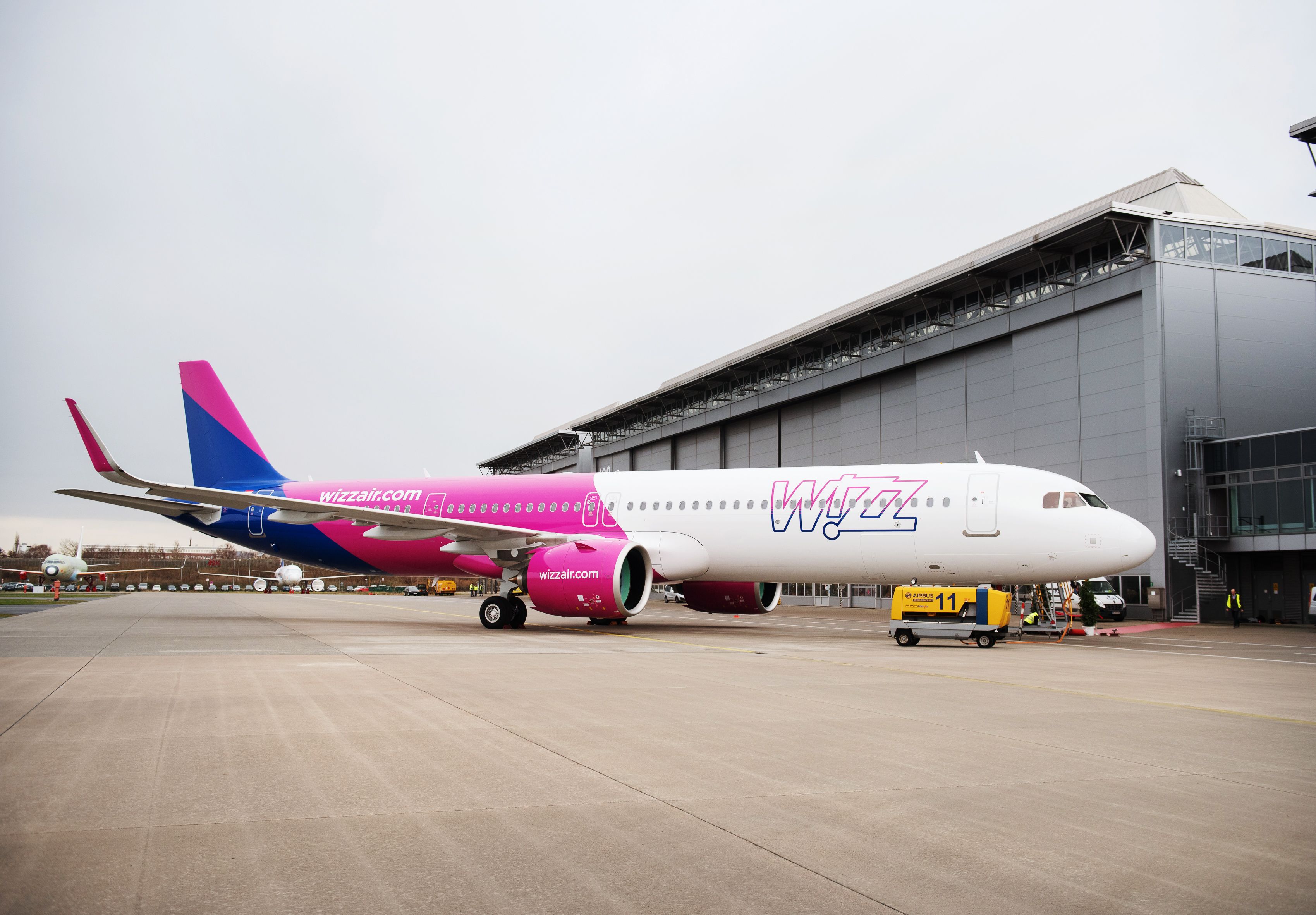 A Wizz Air Airbus A321neo parked outside of a hangar.