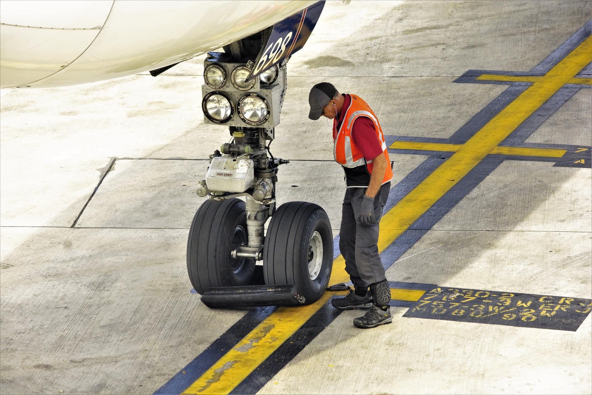 A ground crew member stands next to nose landing gear on an aircraft.