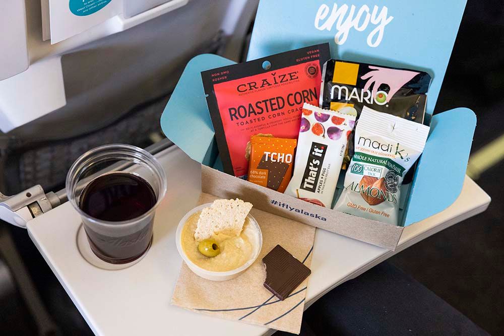 An Alaska Airlines Mediterranean Snack Pack on a seat back tray table.