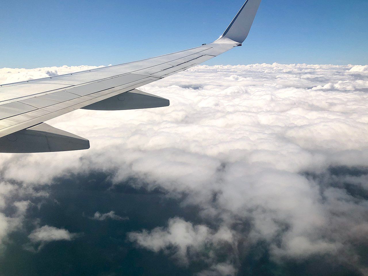 Cabin_window_view_of_clouds_&_aircraft_wing_over_Queensland