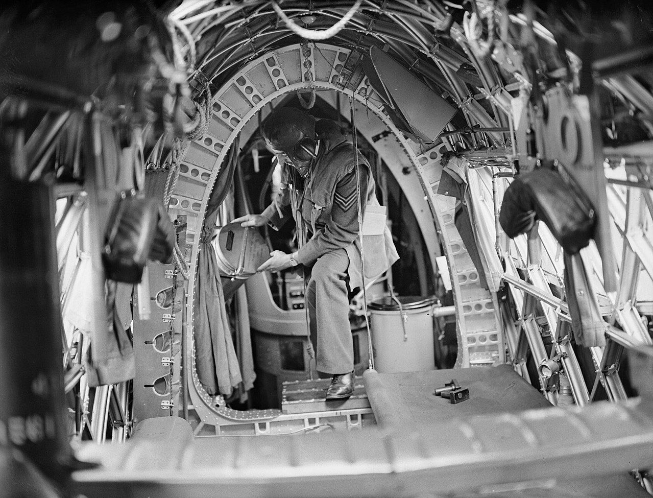 A crew member on board a Vickers Wellington of No. 75 (New Zealand) Squadron RAF places night flares in position in the cramped rear fuselage. Note the Elsan chemical lavatory to the right.