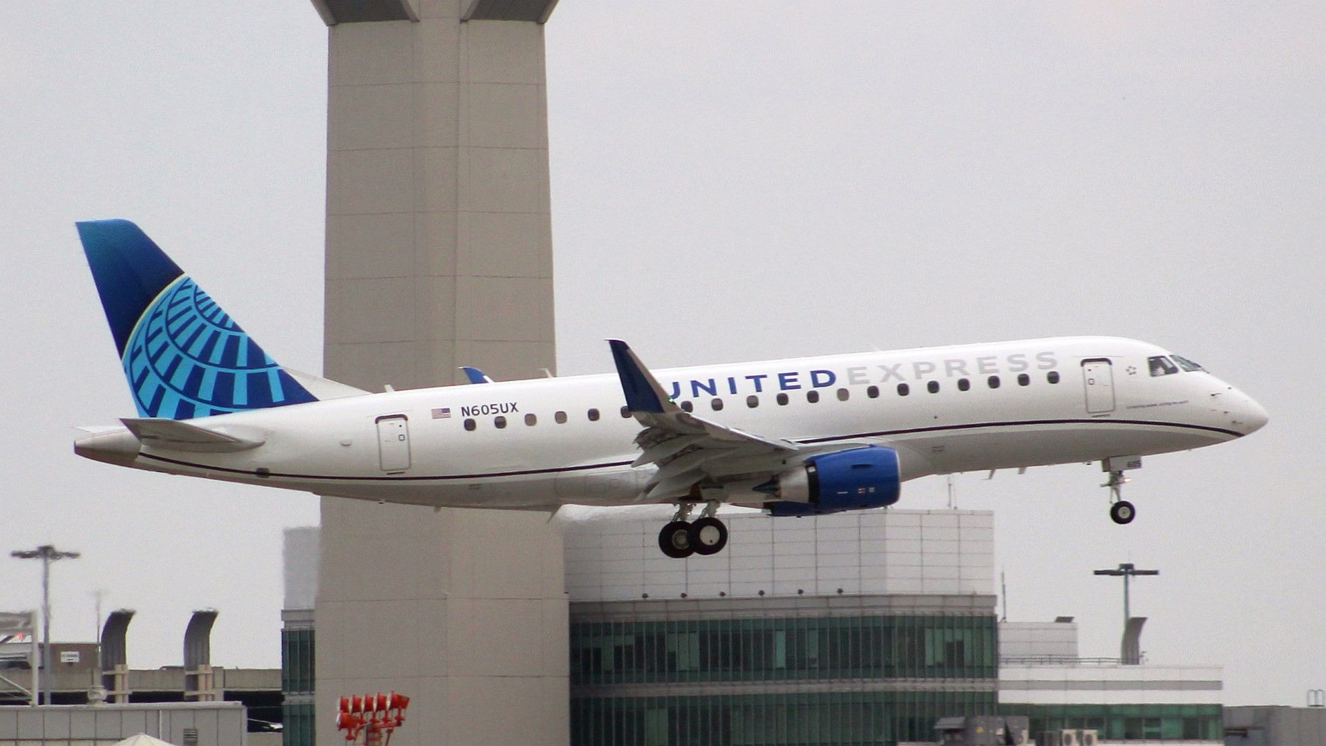 United Airlines ERJ-175 Flying Past An Air Control Tower