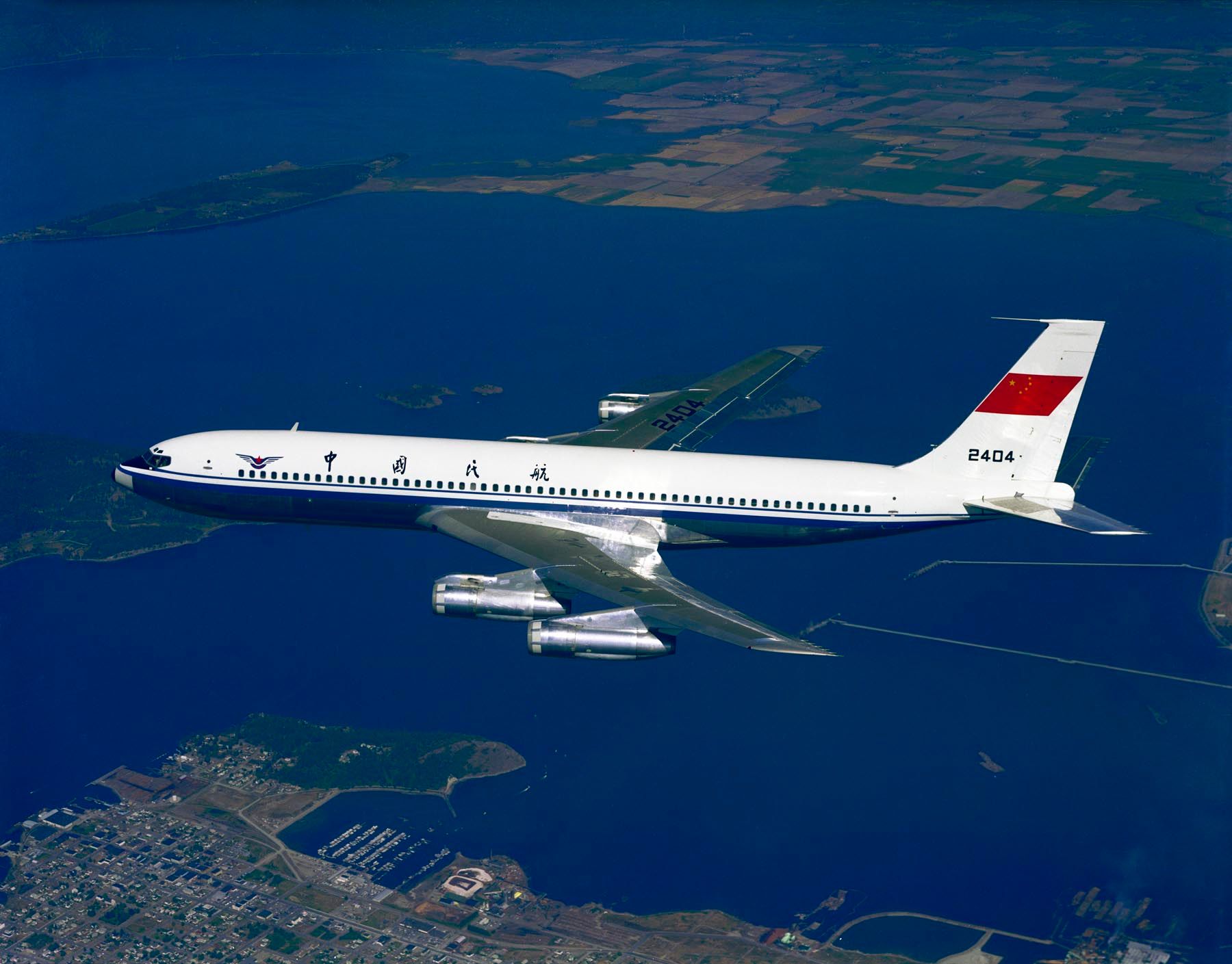 A CAAC Boeing 707 Flying in sky over a coastal area.