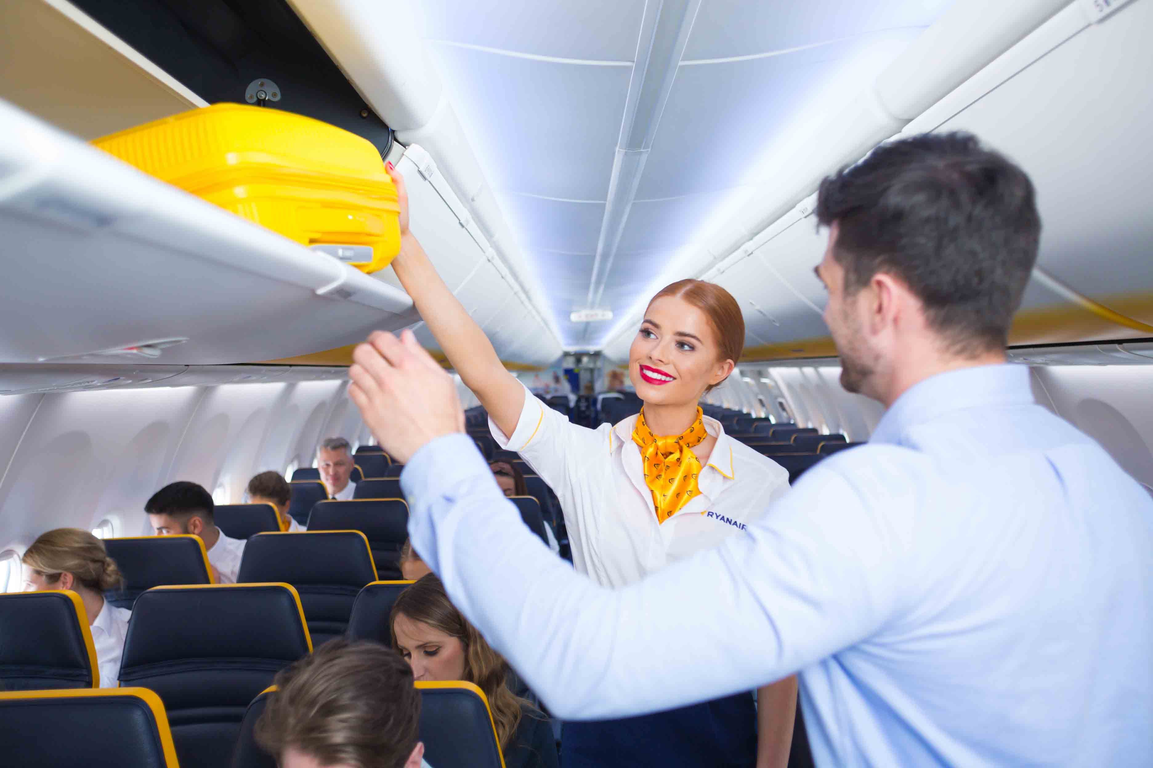 Ryanair cabin crew stowing baggage in overhead locker
