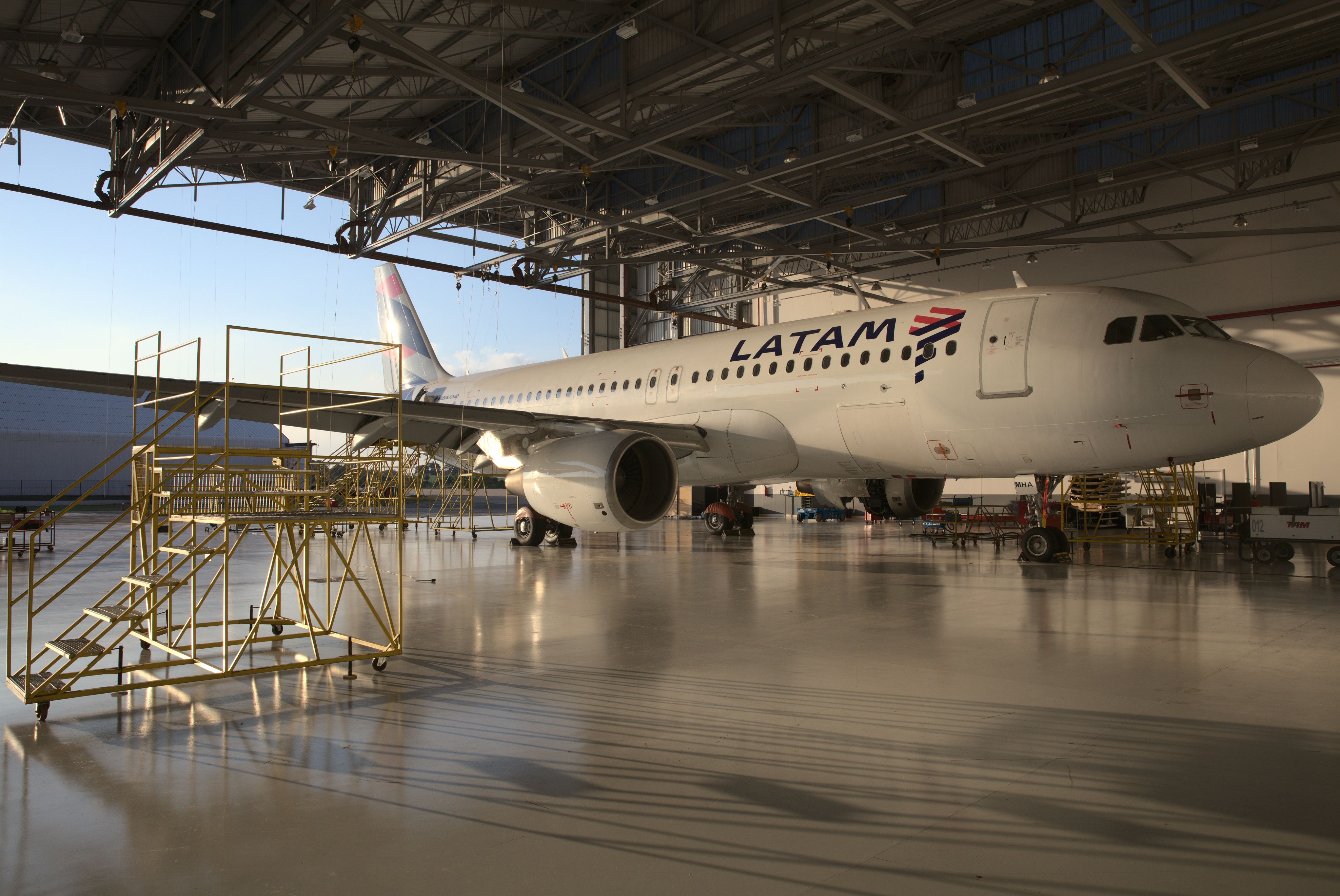 A LATAM Airbus A320-family aircraft parked inside a hangar. 
