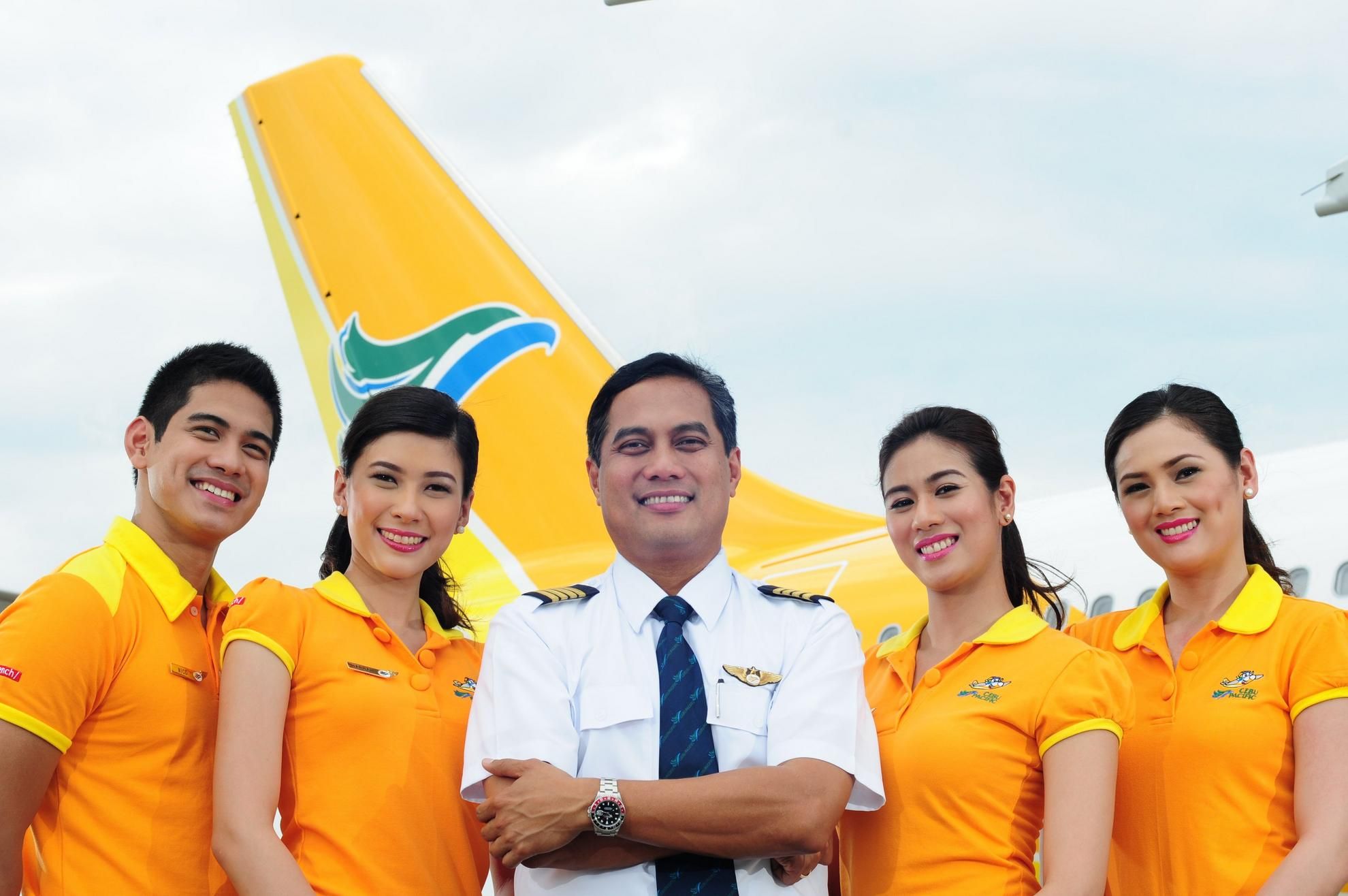 Cebu Pacific cabin crew in front of an aircraft tail