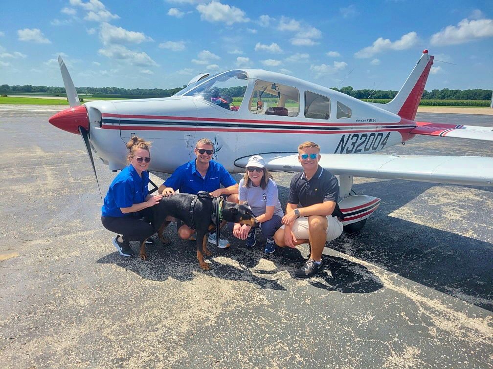 pilots and volunteers in front of aircraft with rescued animal