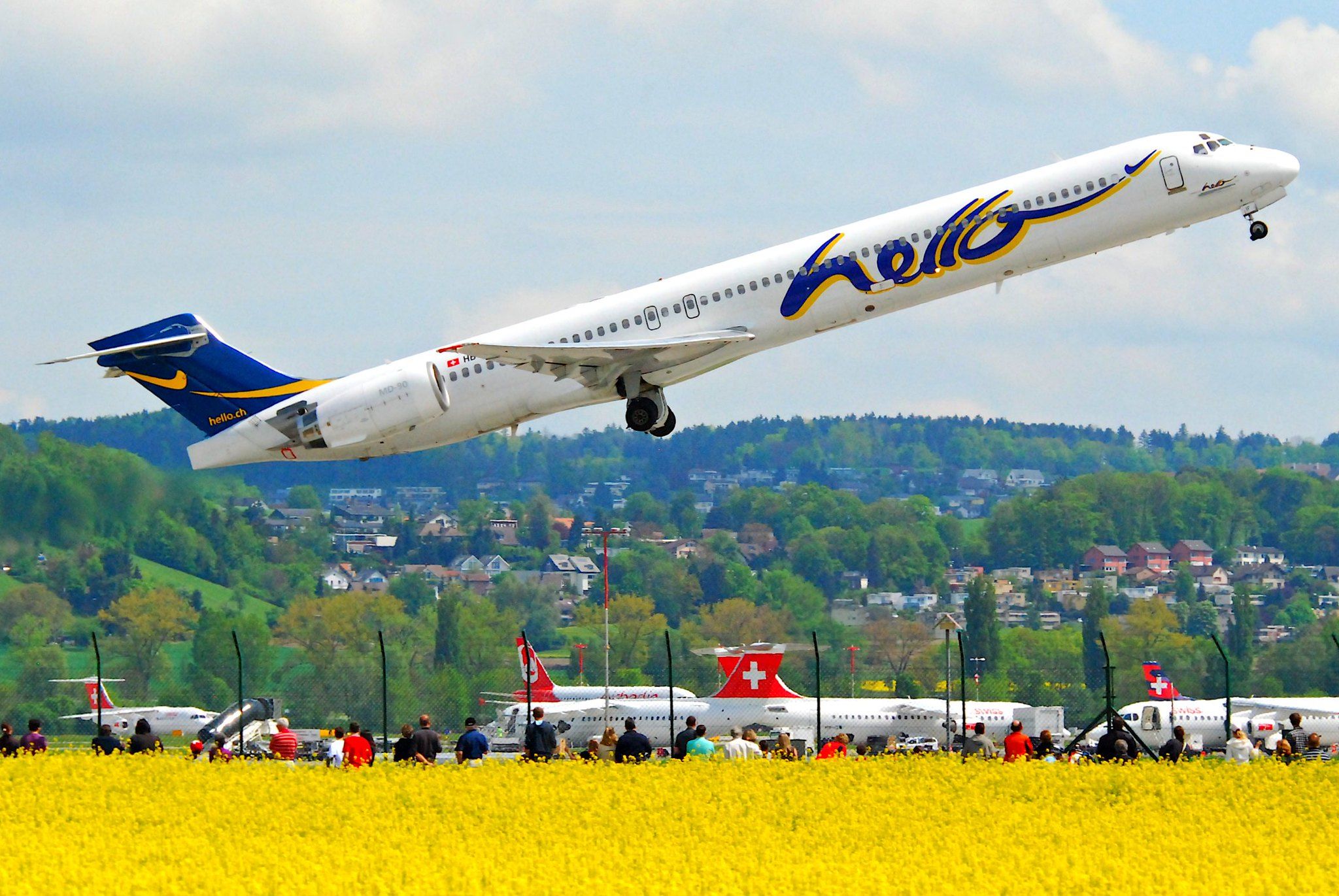 Hello Airlines MD-90 taking off, with many SWISS aircraft parked in the background.