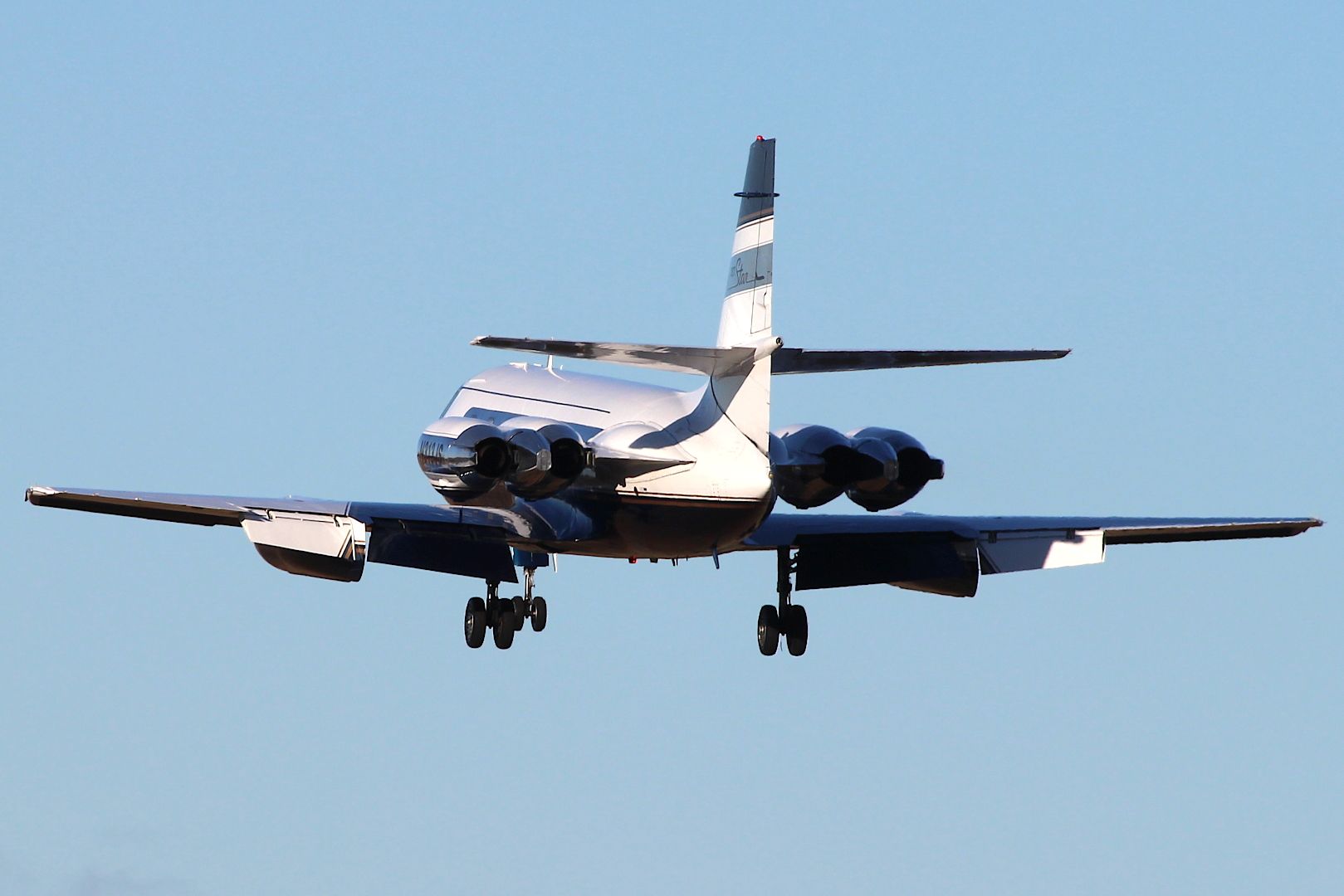 Lockheed JetStar taking off against blue sky