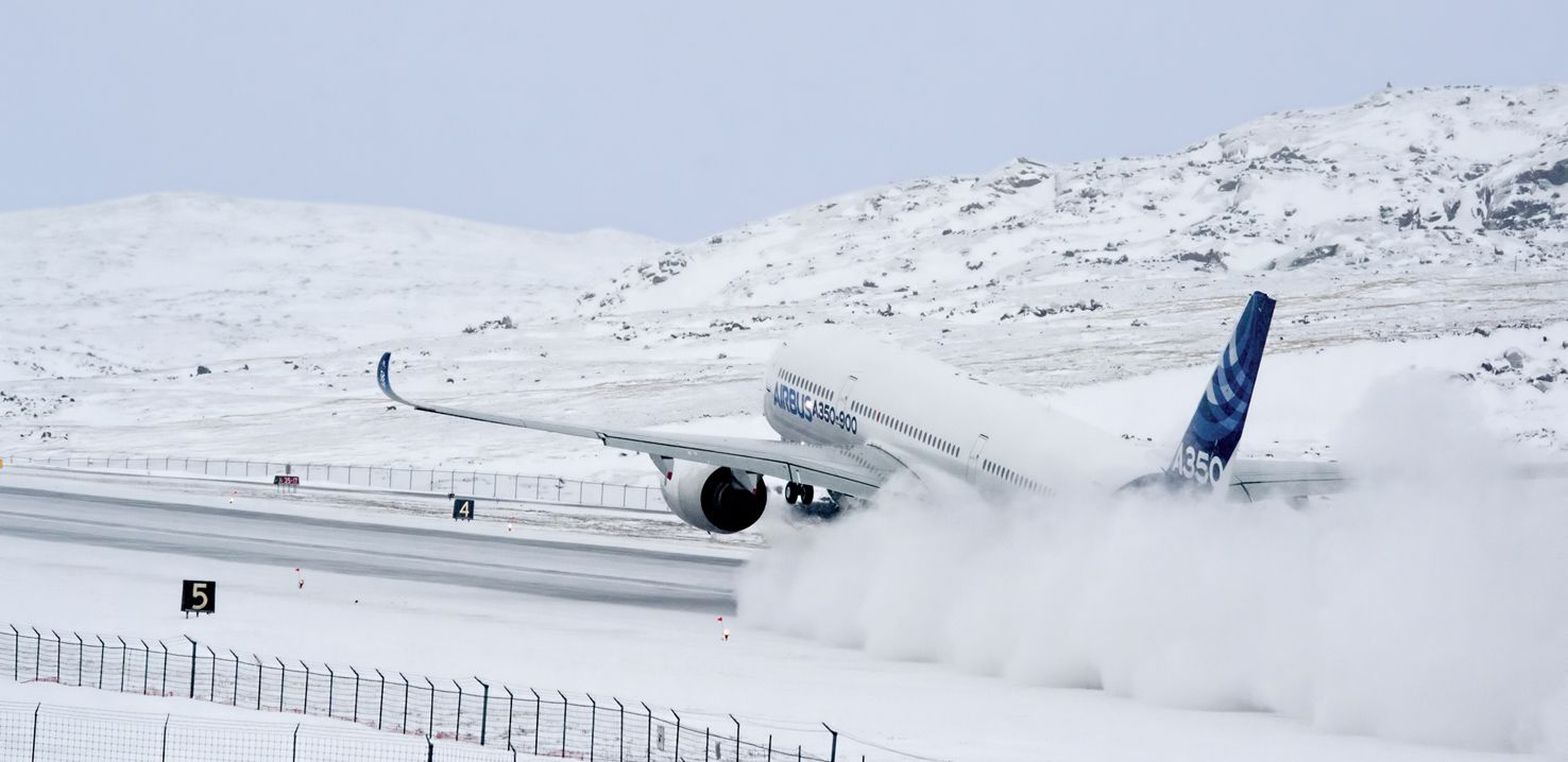 An Airbus A350 landing on a snowy runway.
