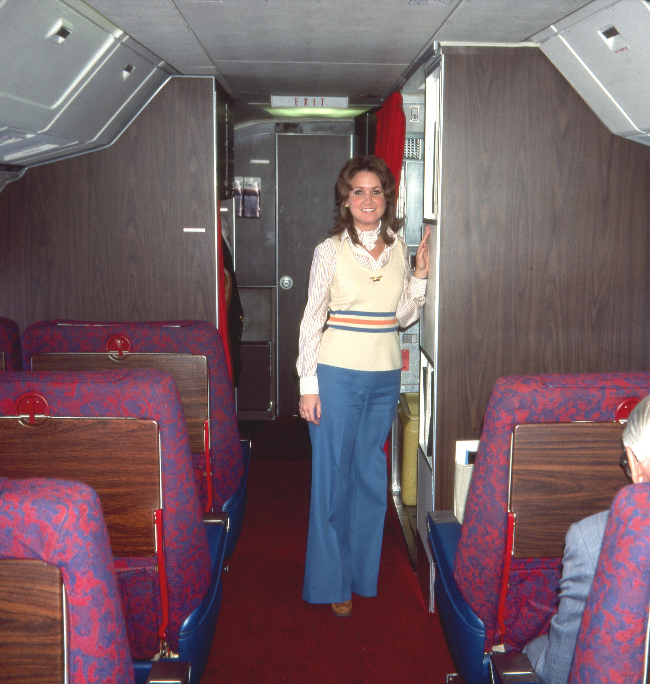 A Delta Air Lines flight attendent stnading in the cabin of a Boeing 727.